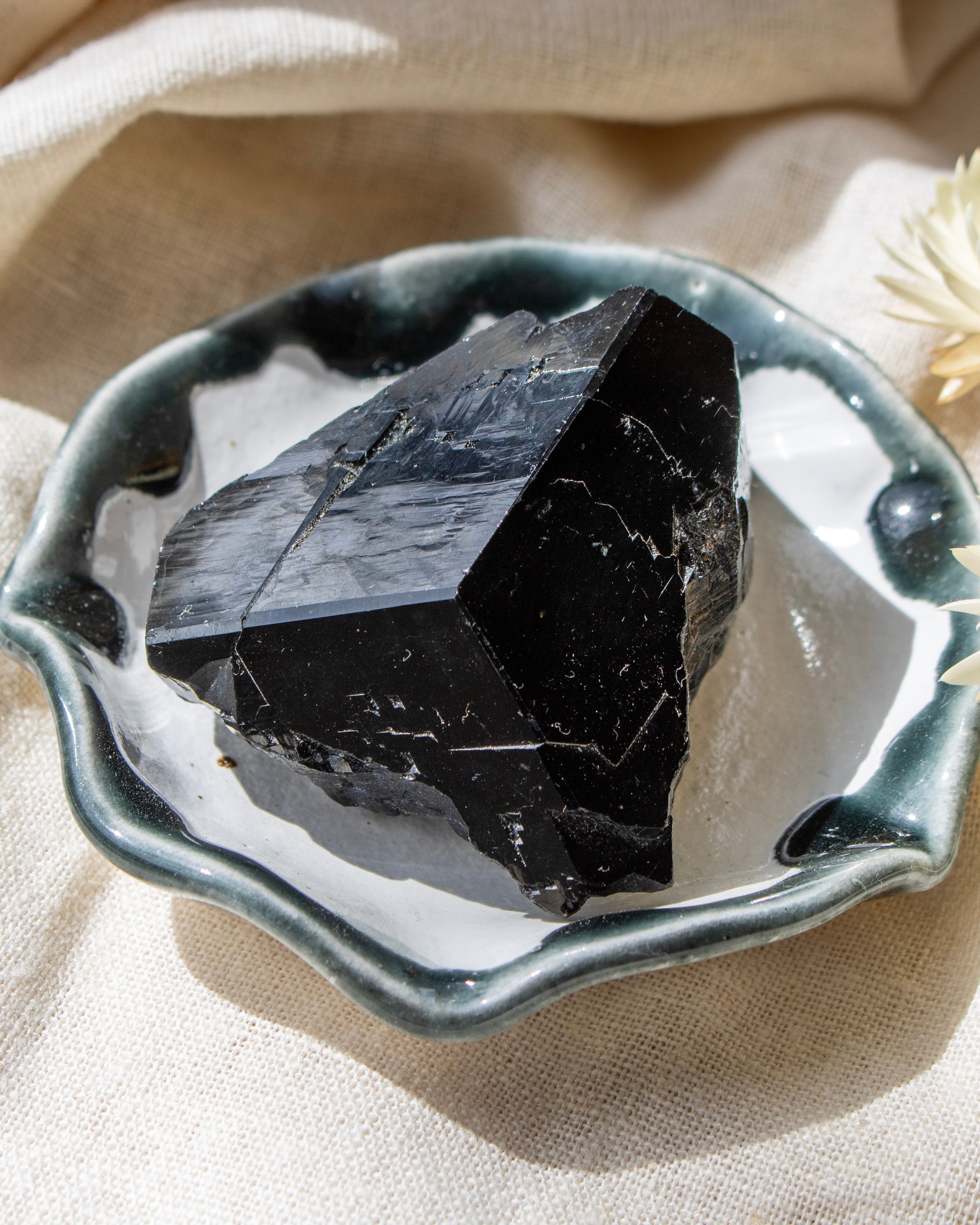 Black crystal on a decorative ceramic dish with a beige fabric background