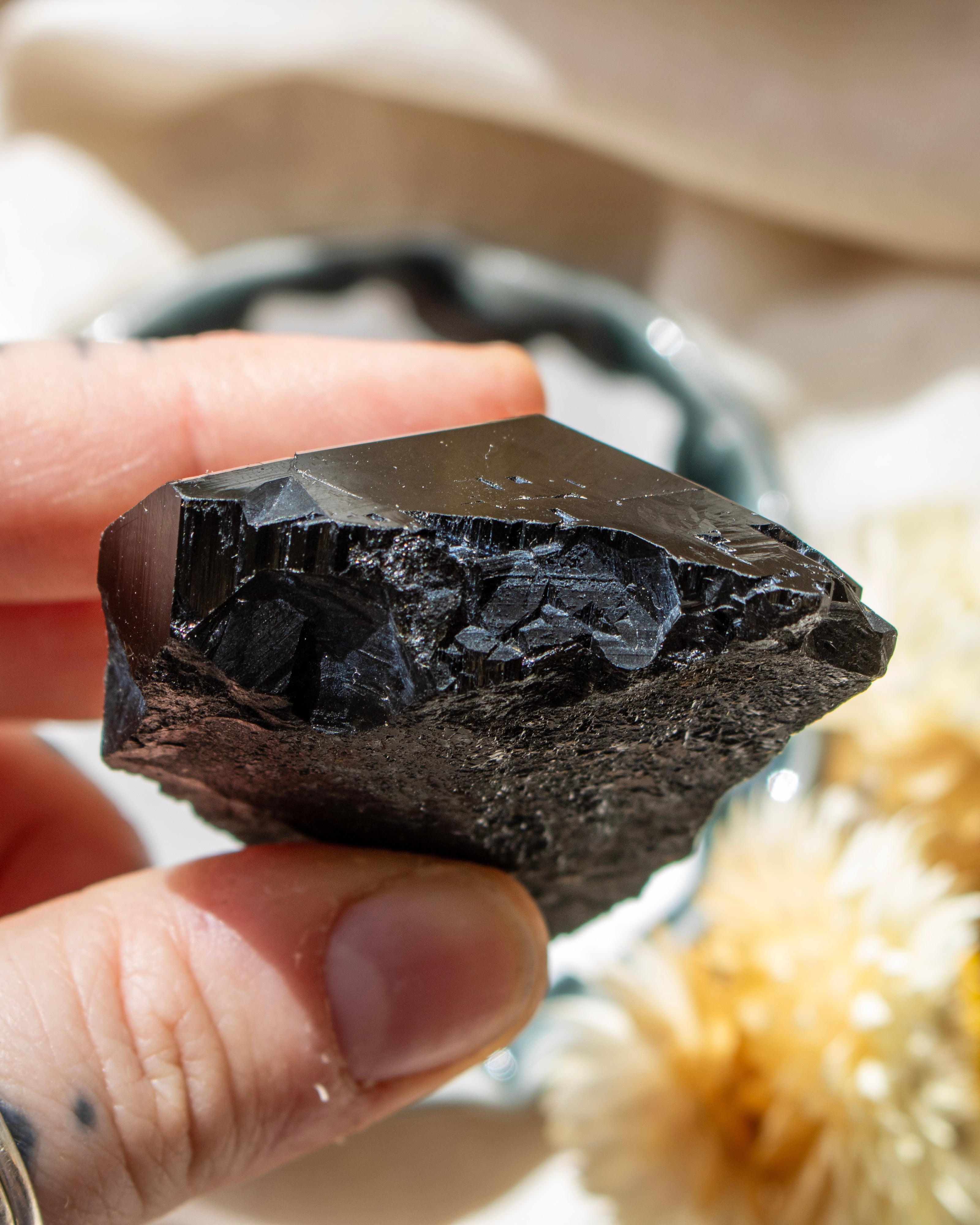 Person holding a dark crystal rock with a blurred natural background