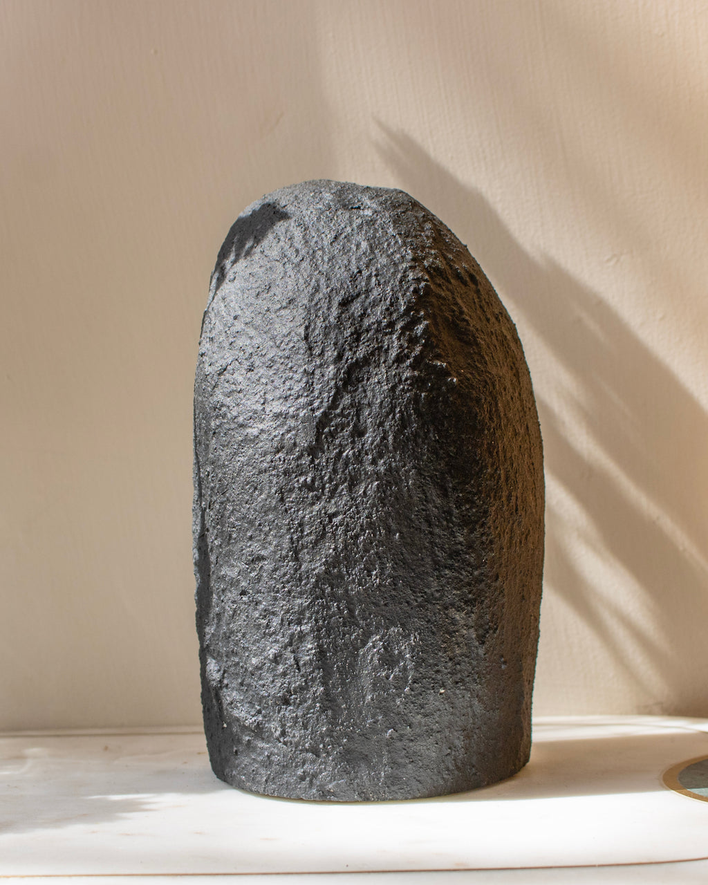 Large gray stone on a white surface with a beige background