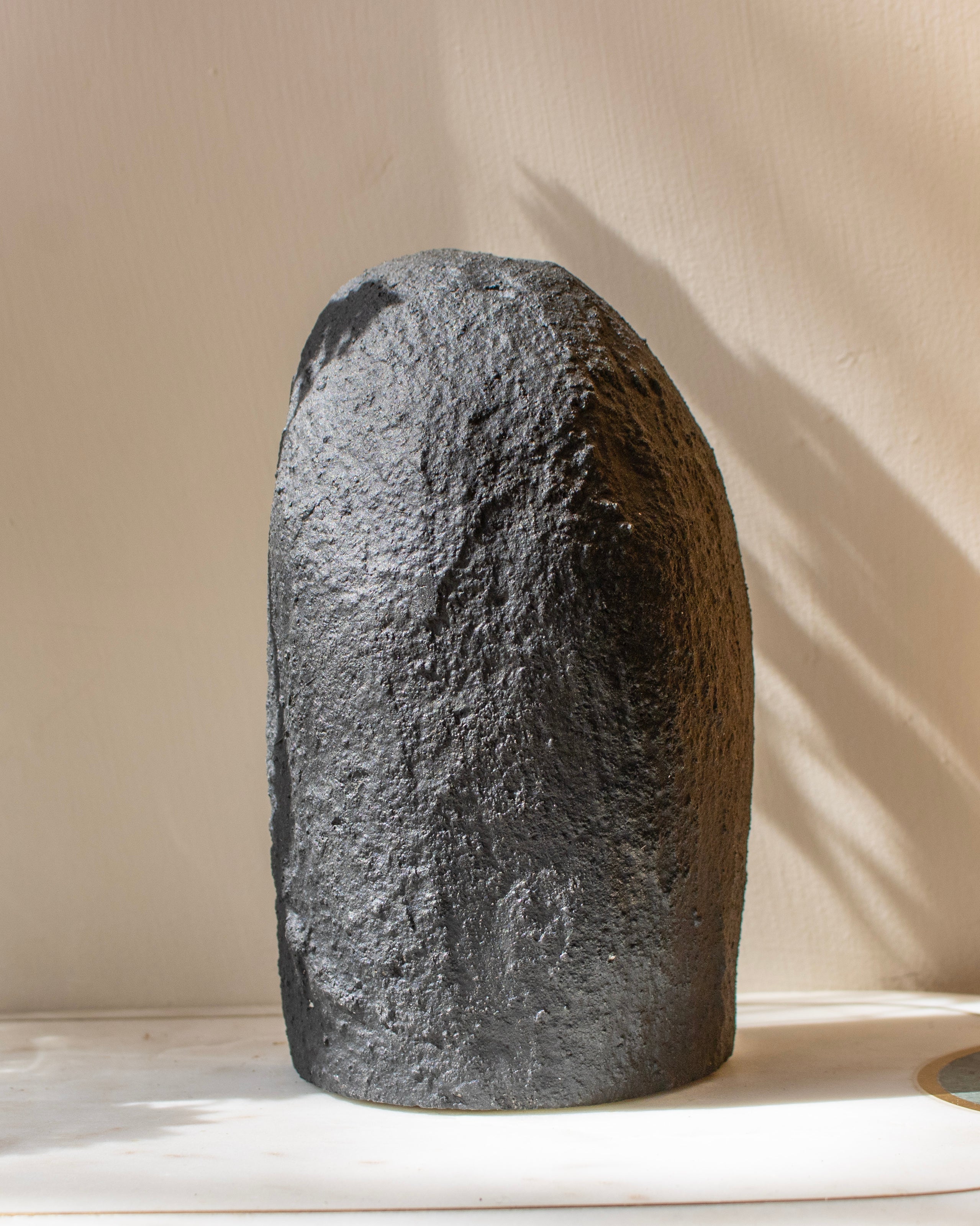 Large gray stone on a white surface with a beige background