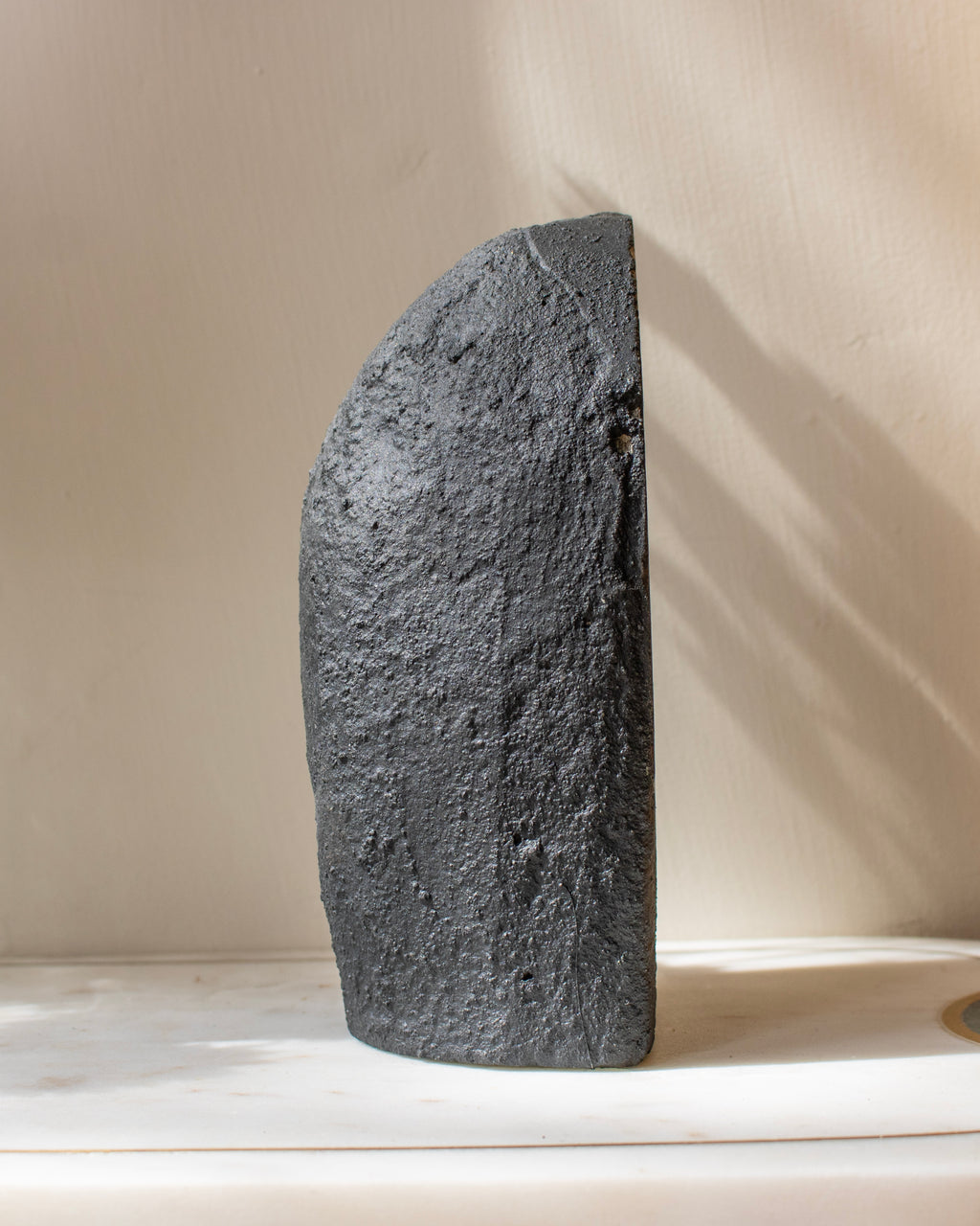 Dark stone sculpture on a light surface with a neutral background