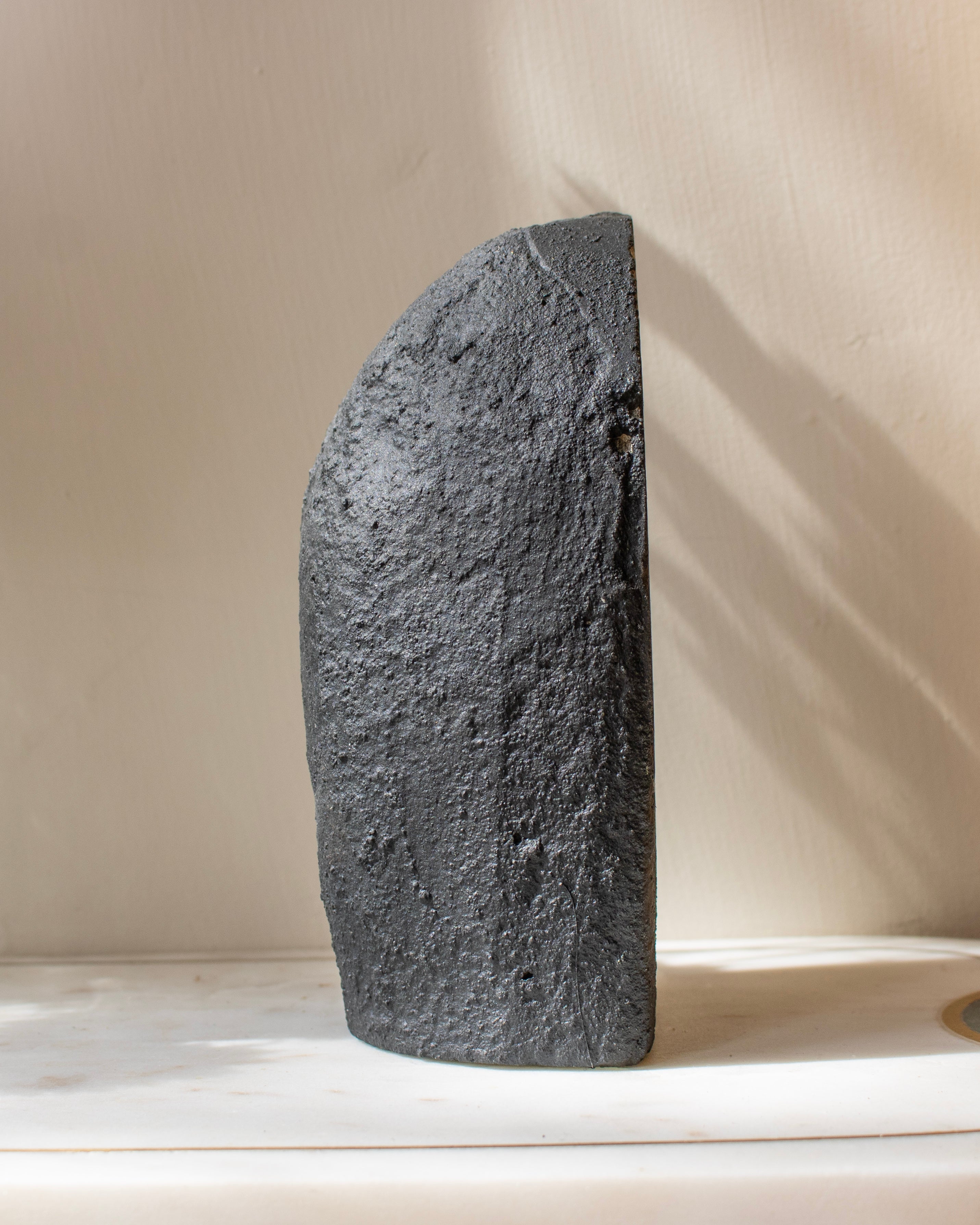 Dark stone sculpture on a light surface with a neutral background