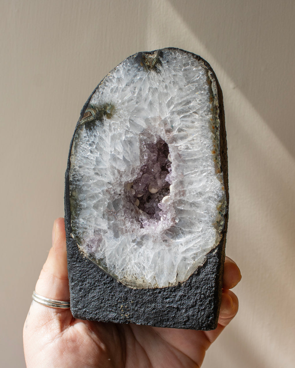 Geode held in a hand with a neutral background