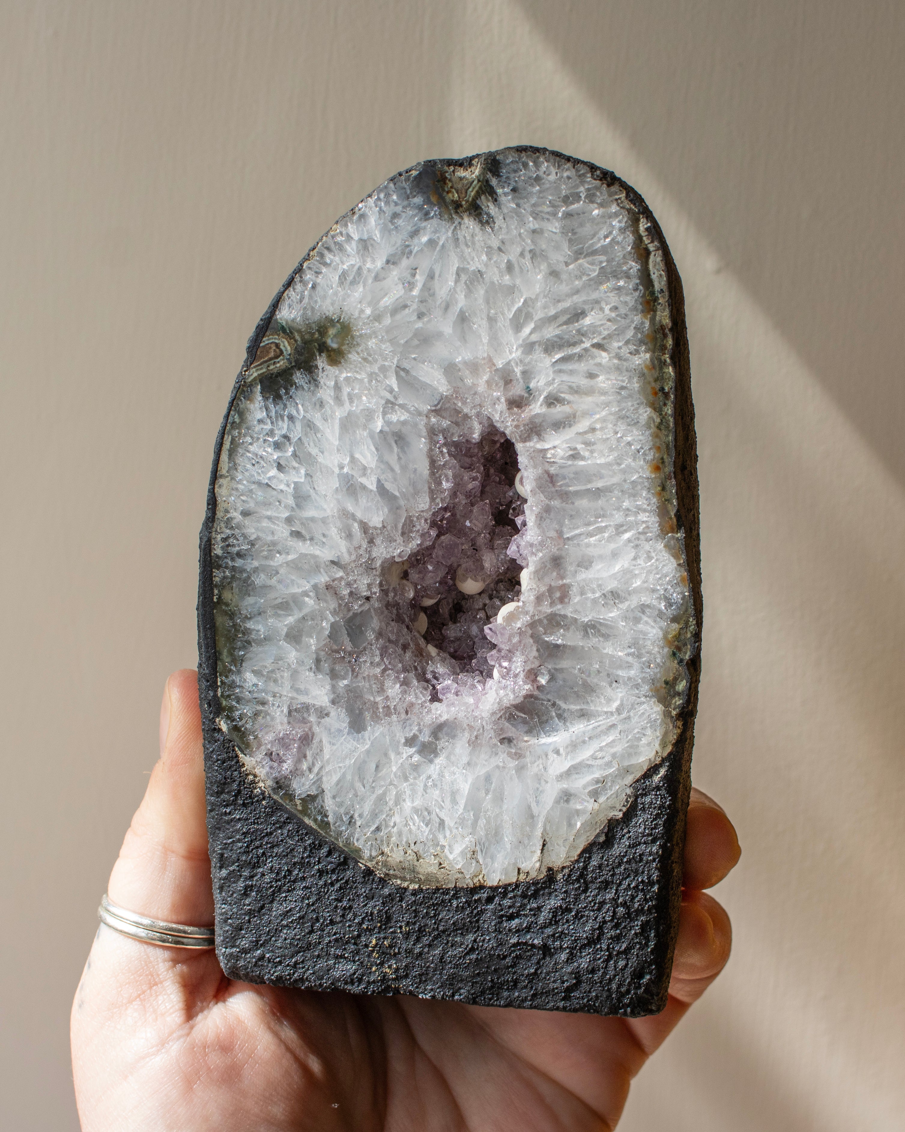 Geode held in a hand with a neutral background