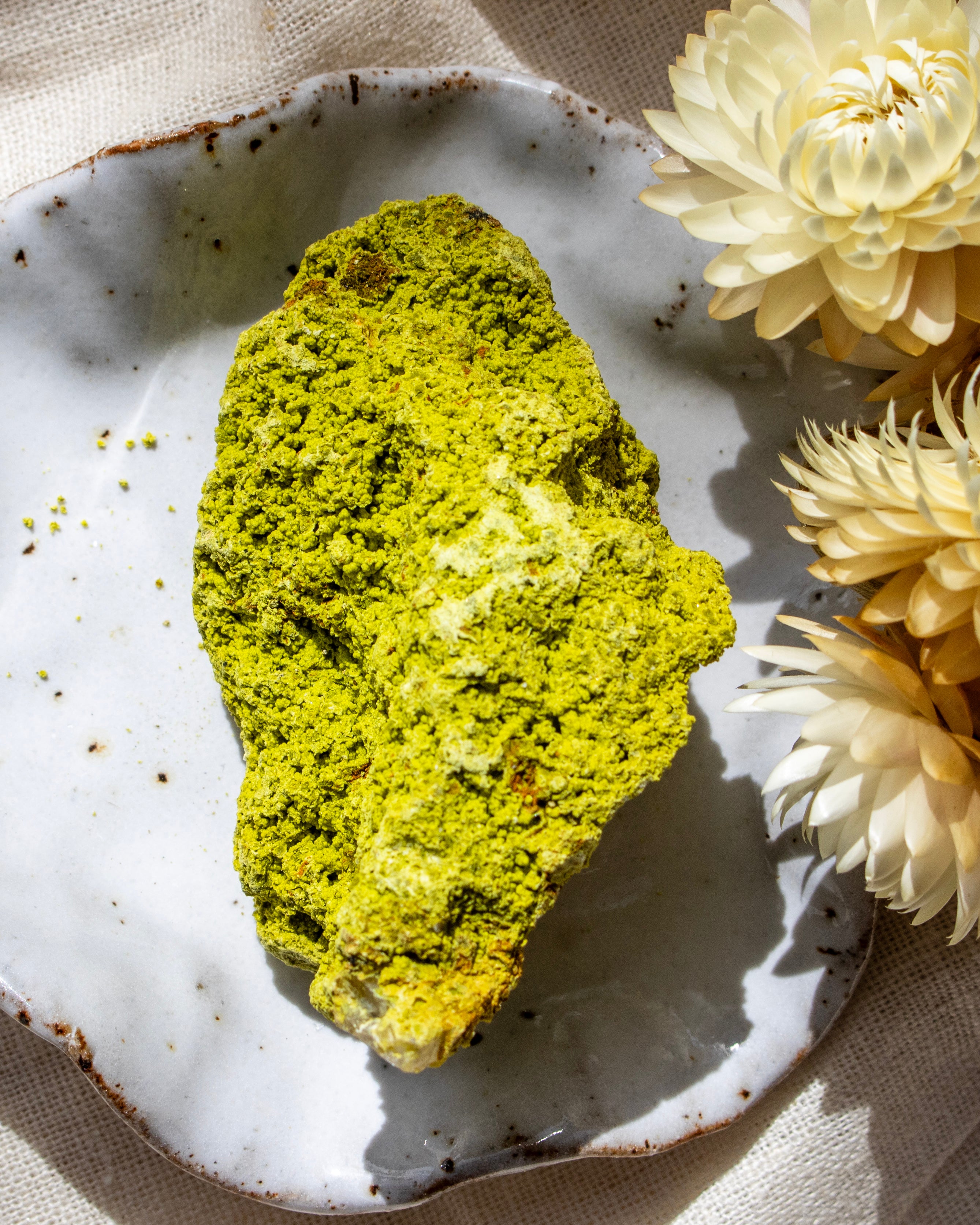 Green crumbly stone on a textured plate with yellow flowers