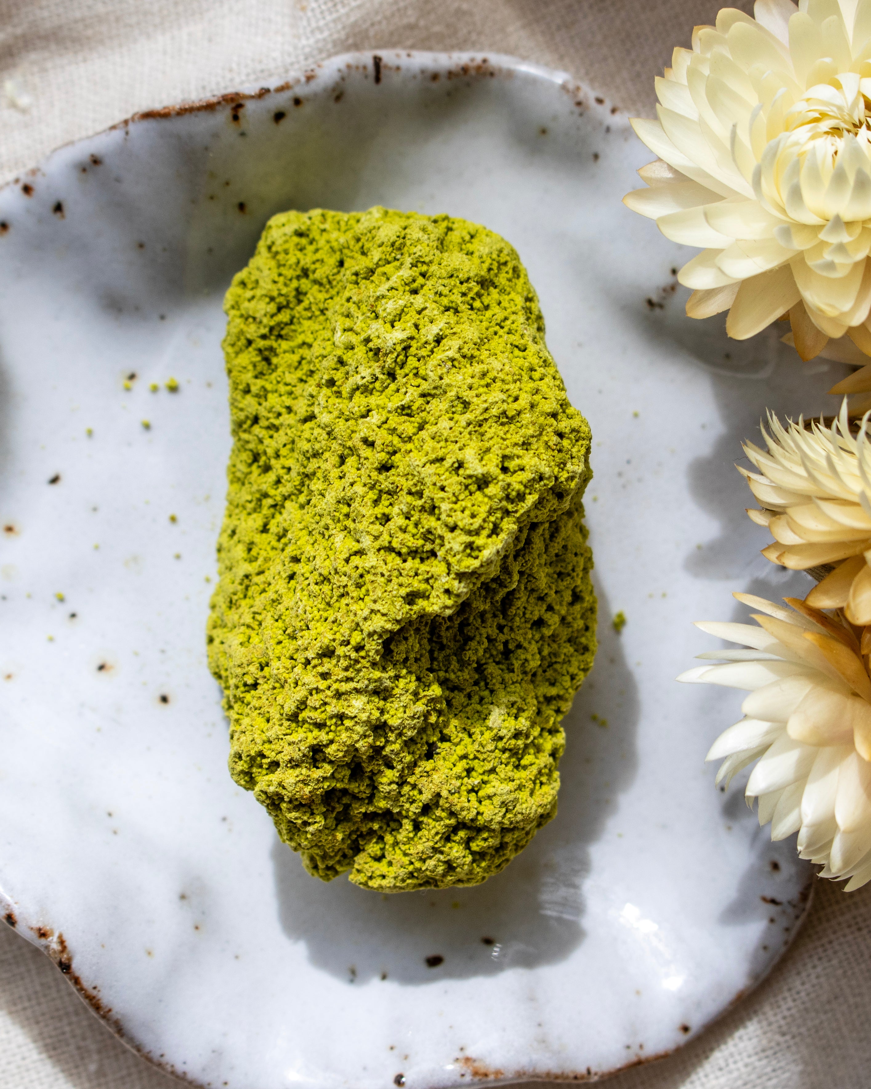 Green stone on a white ceramic plate with yellow flowers