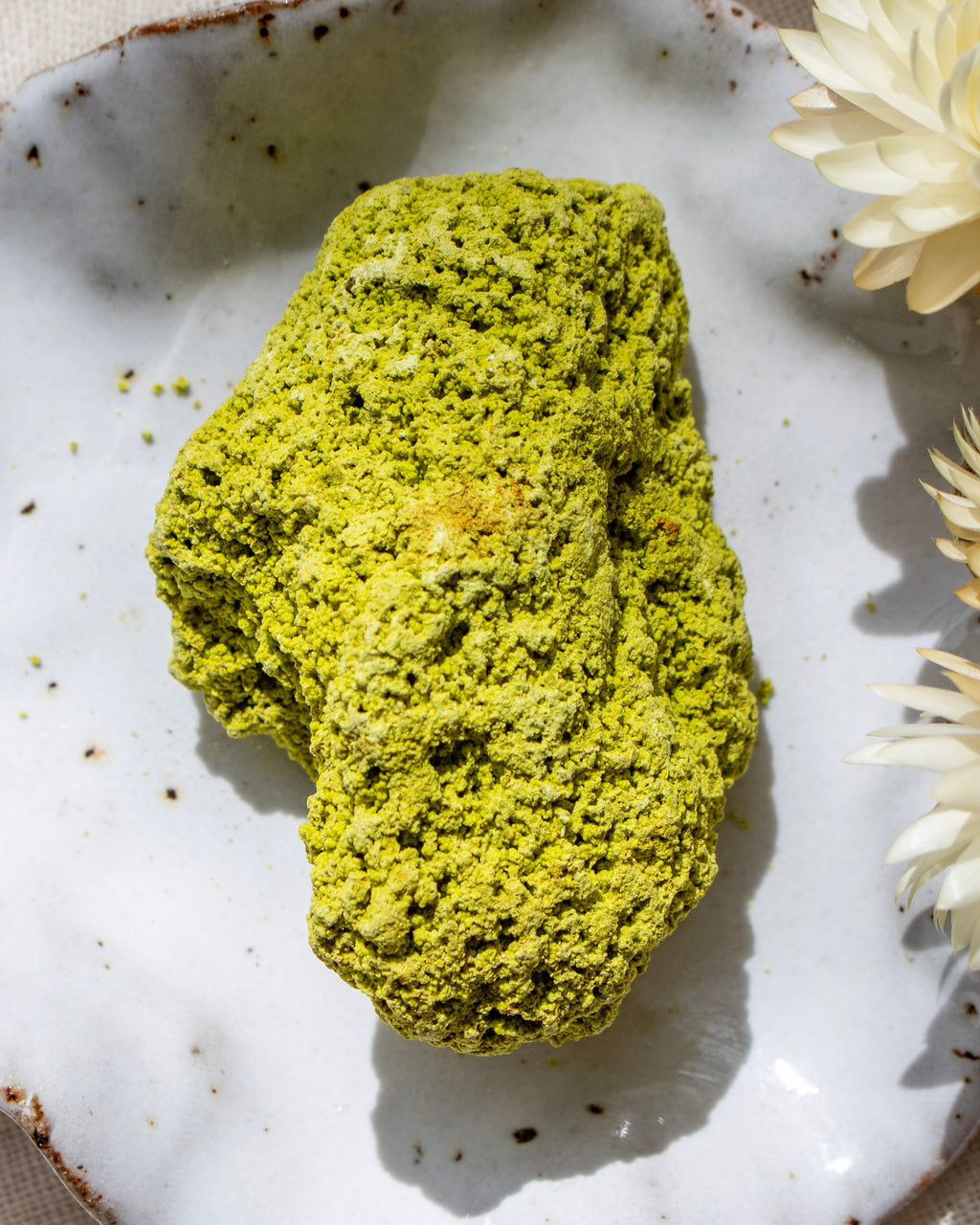 Green stone on a textured white plate with flowers
