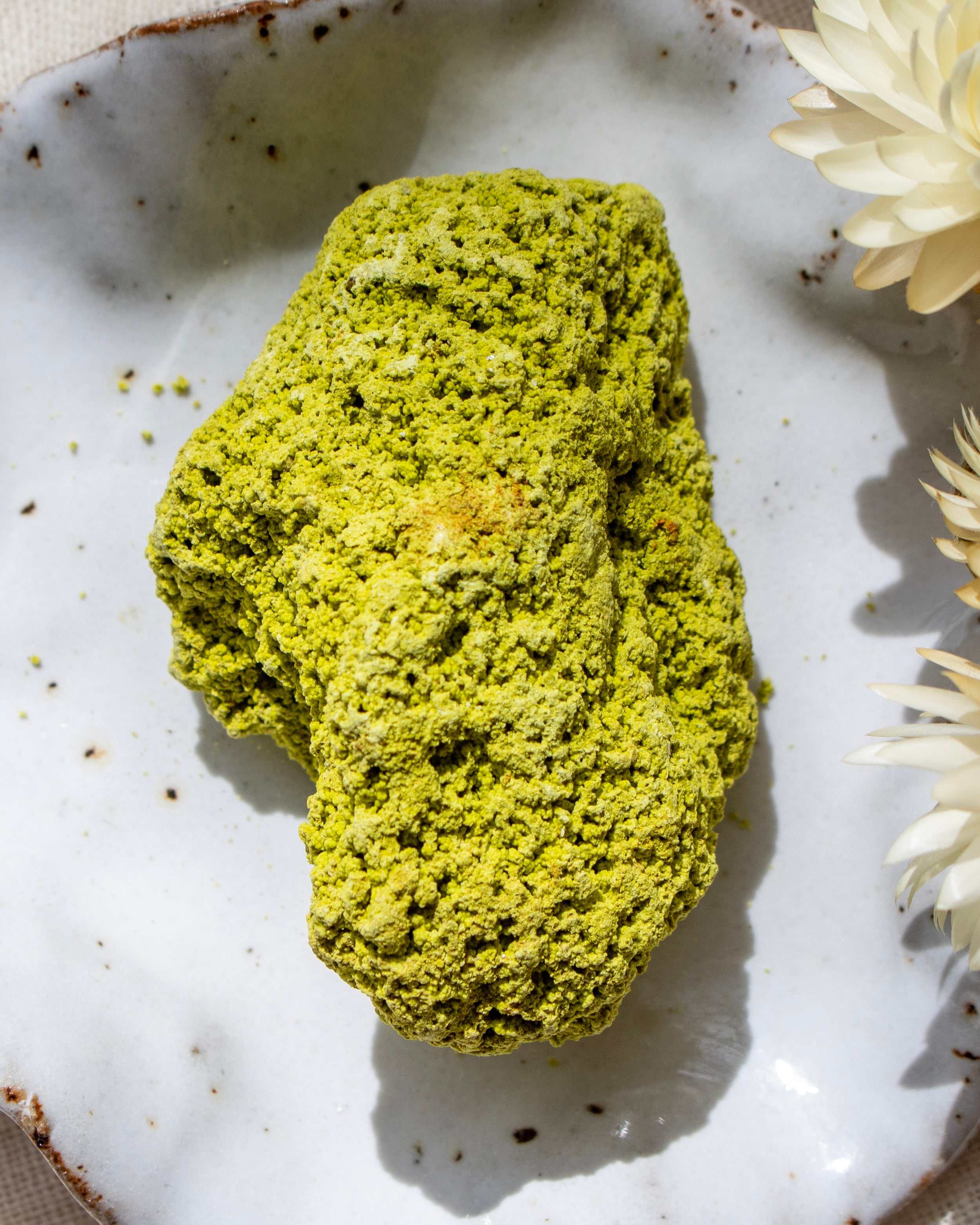 Green stone on a textured white plate with flowers