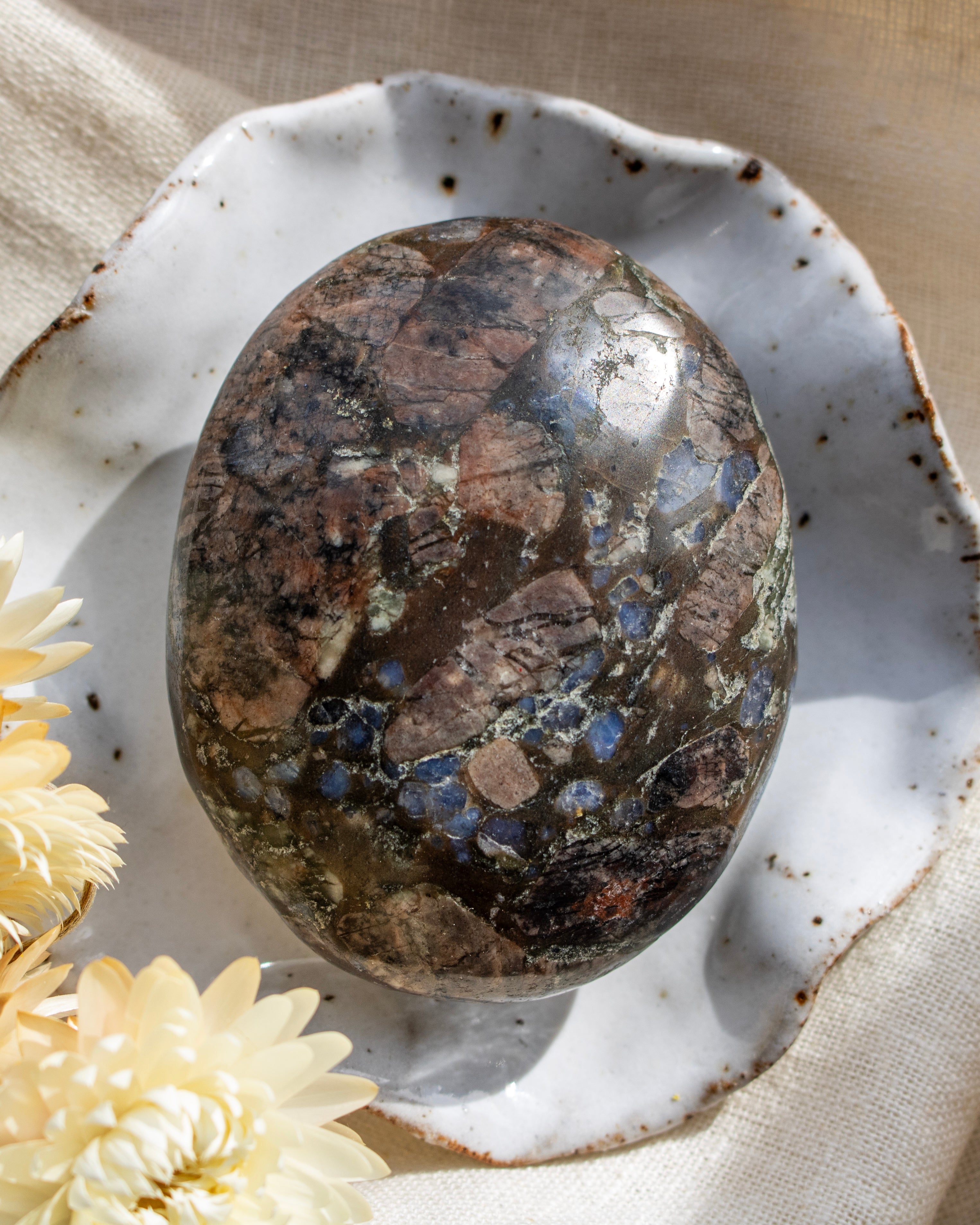 Polished stone on a textured ceramic plate with flowers