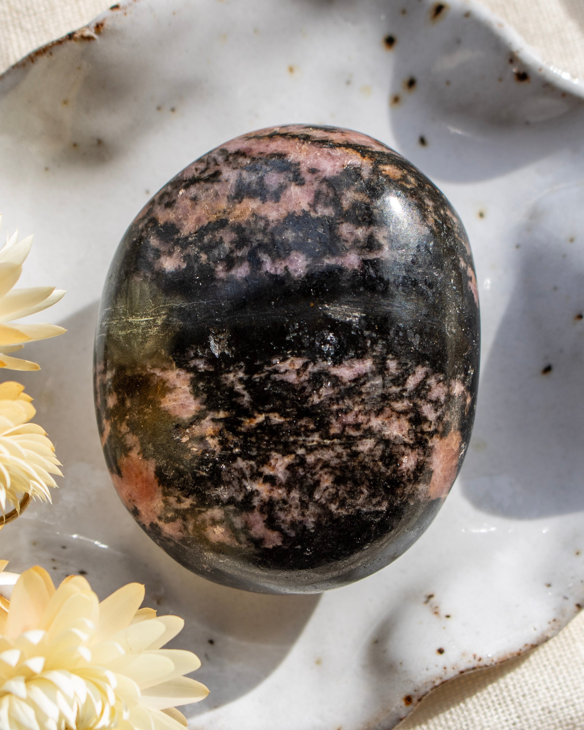Polished multicolored stone on a textured surface with flowers