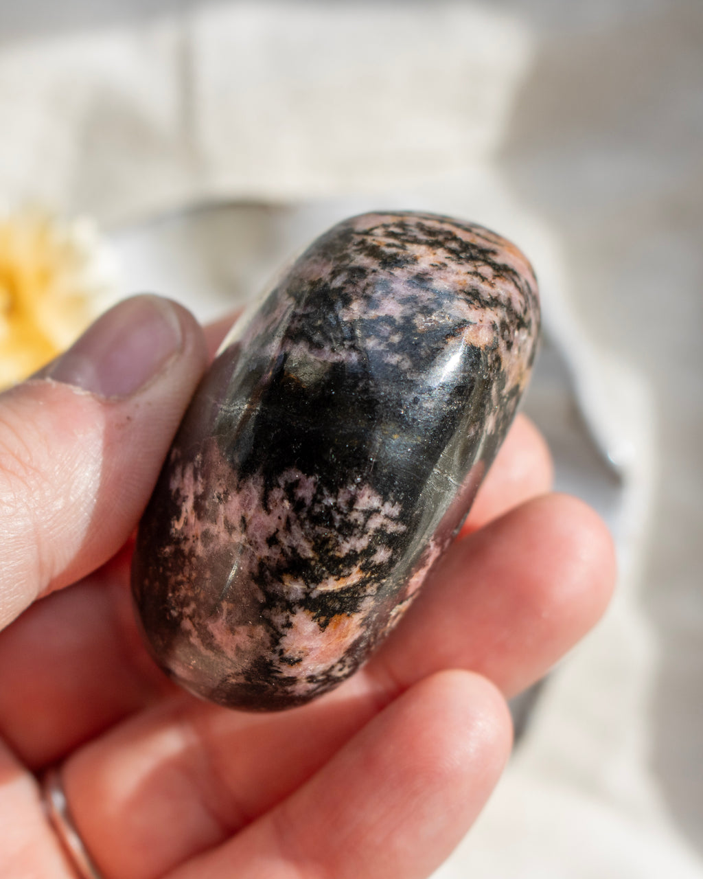 Hand holding a polished stone with a marbled pattern against a blurred background