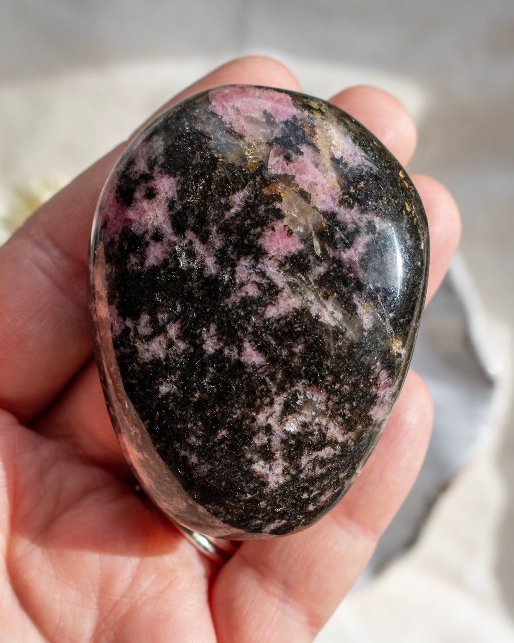Person holding a polka dot rhodonite stone