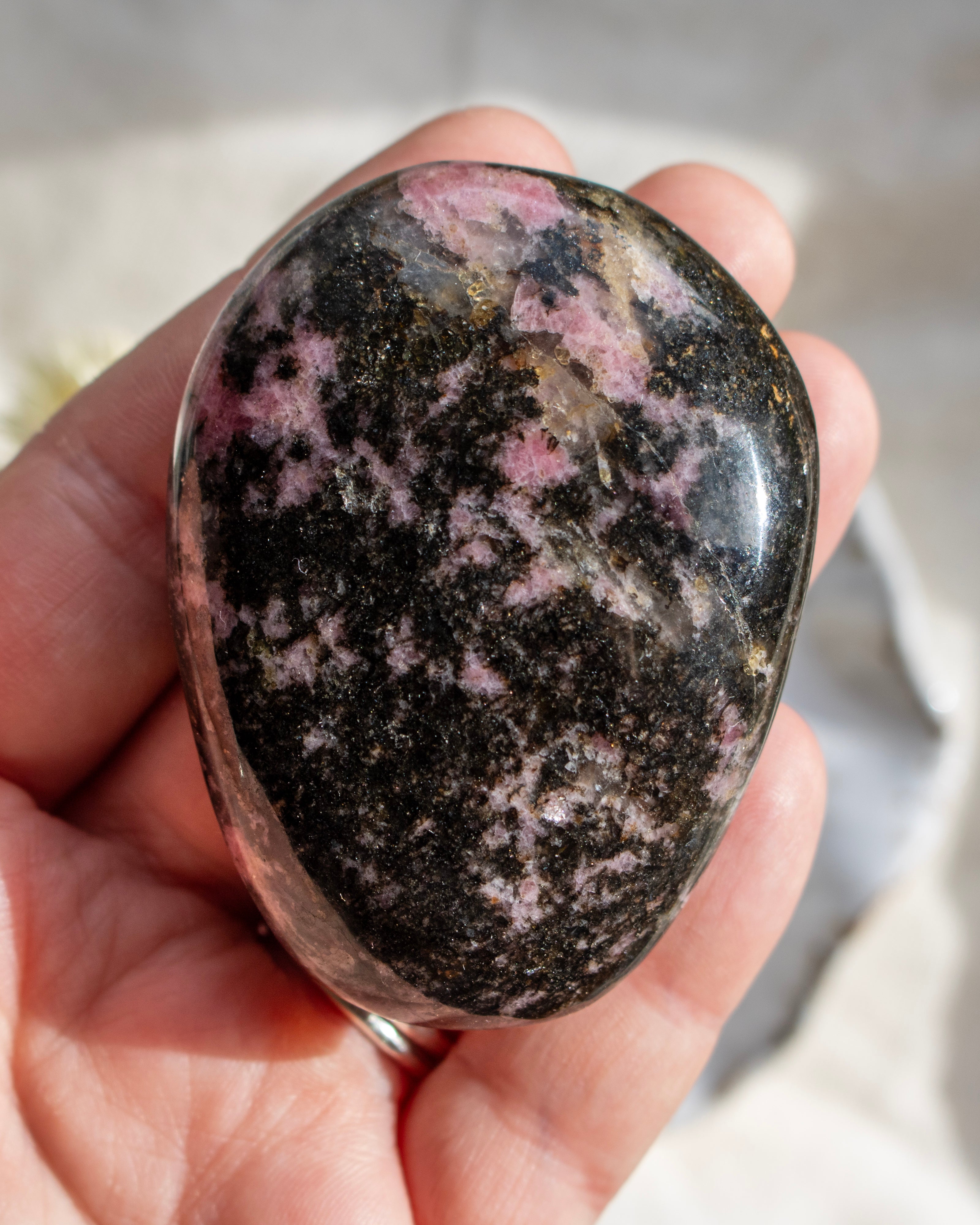 Person holding a polka dot rhodonite stone