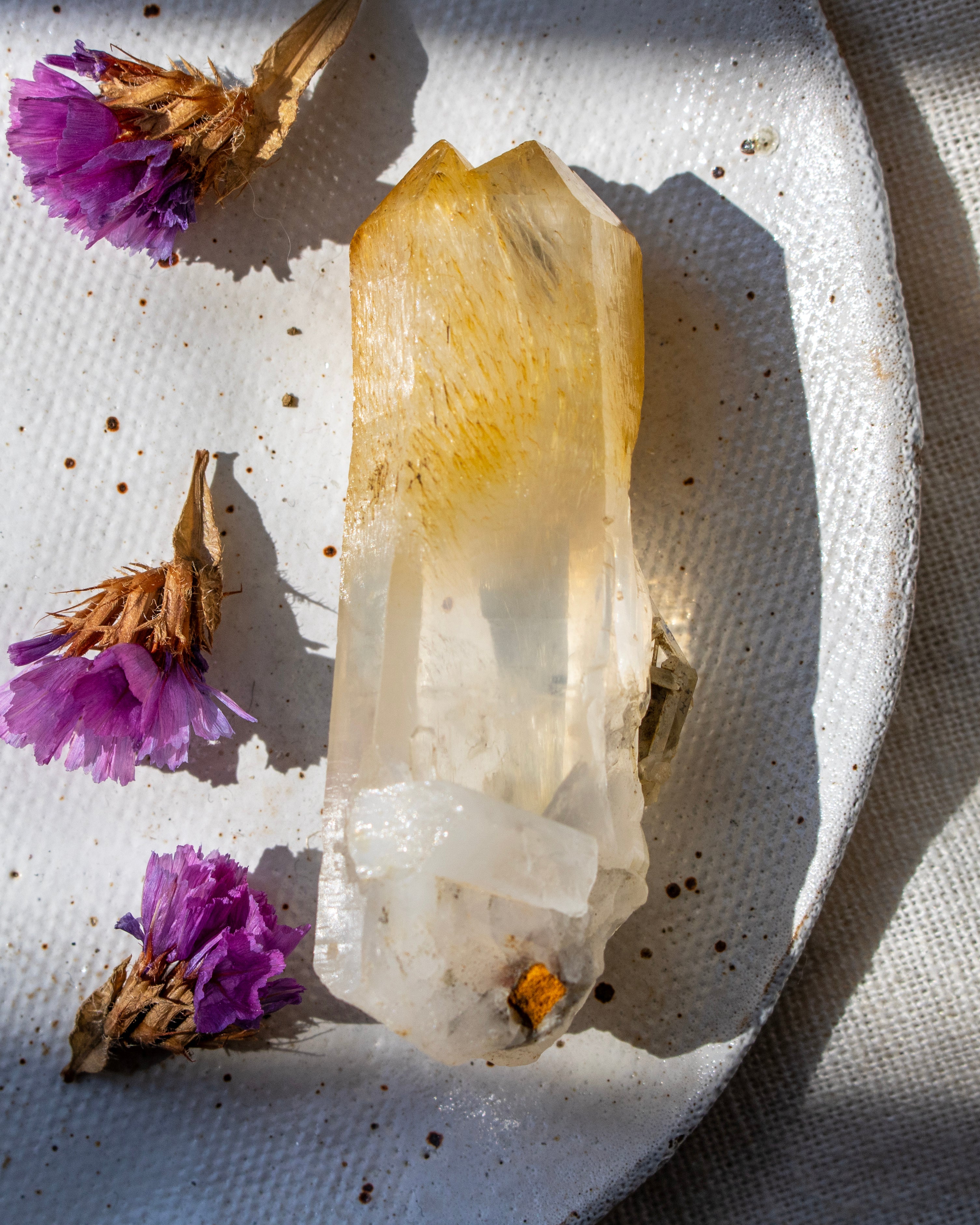 Crystal on a textured surface with purple flowers