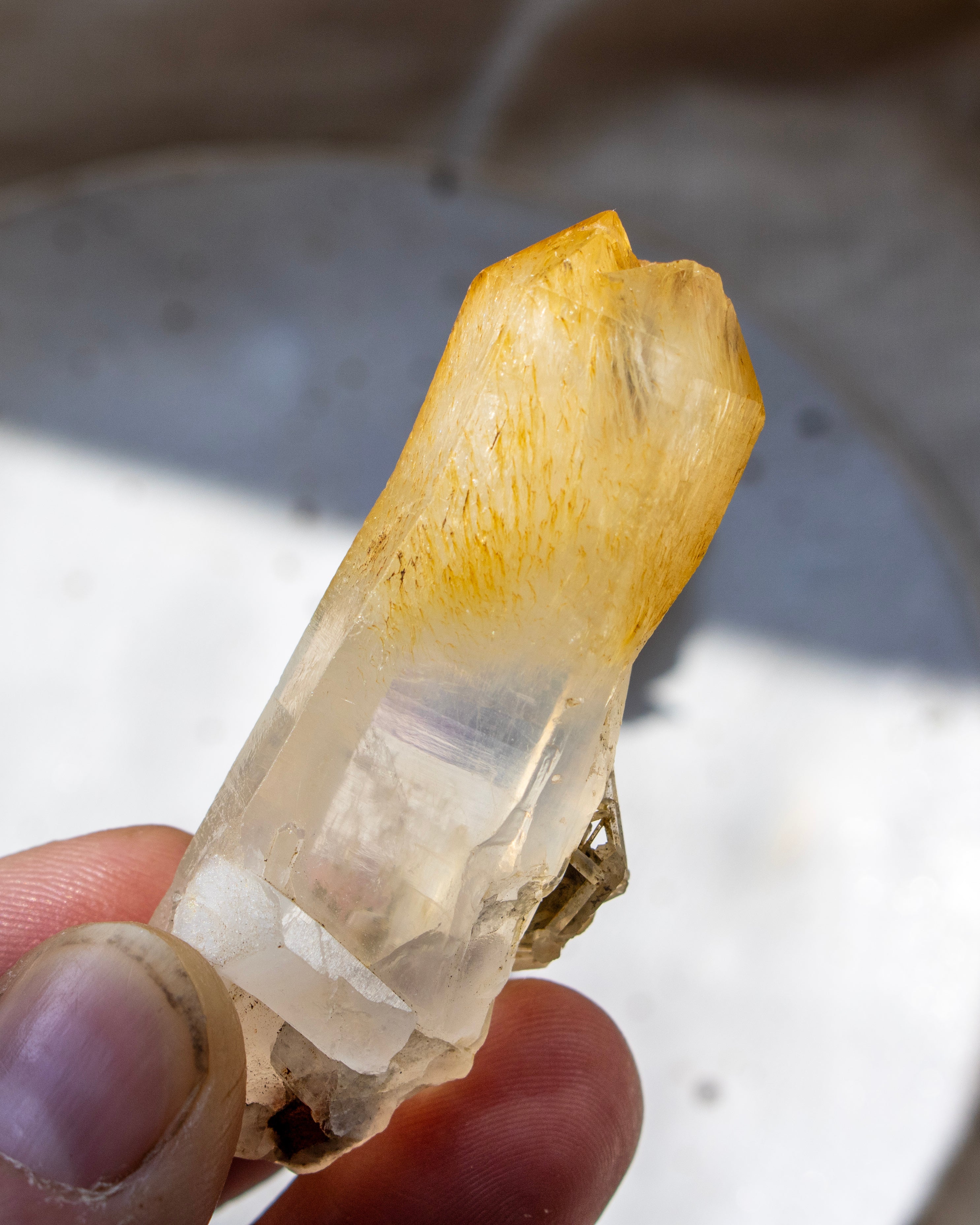 Clear crystal held in a hand with a blurred background