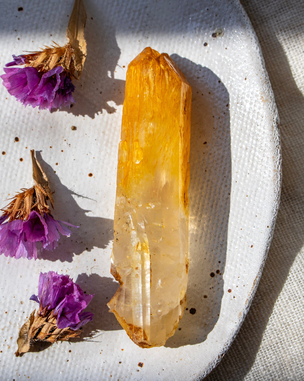 Clear crystal on a textured white surface with purple flowers