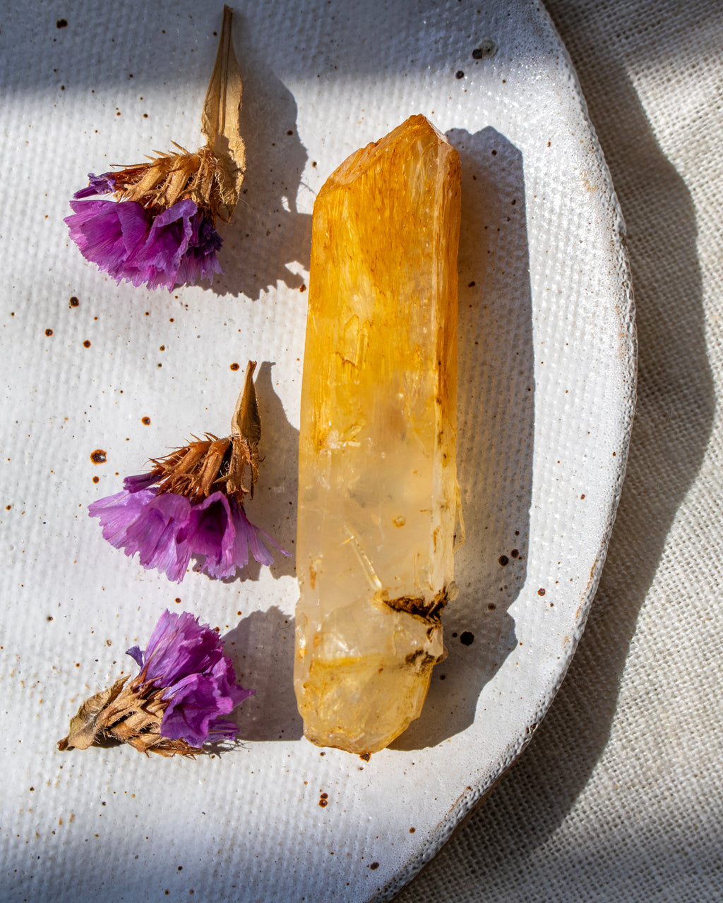 Clear crystal on a textured white surface with purple flowers