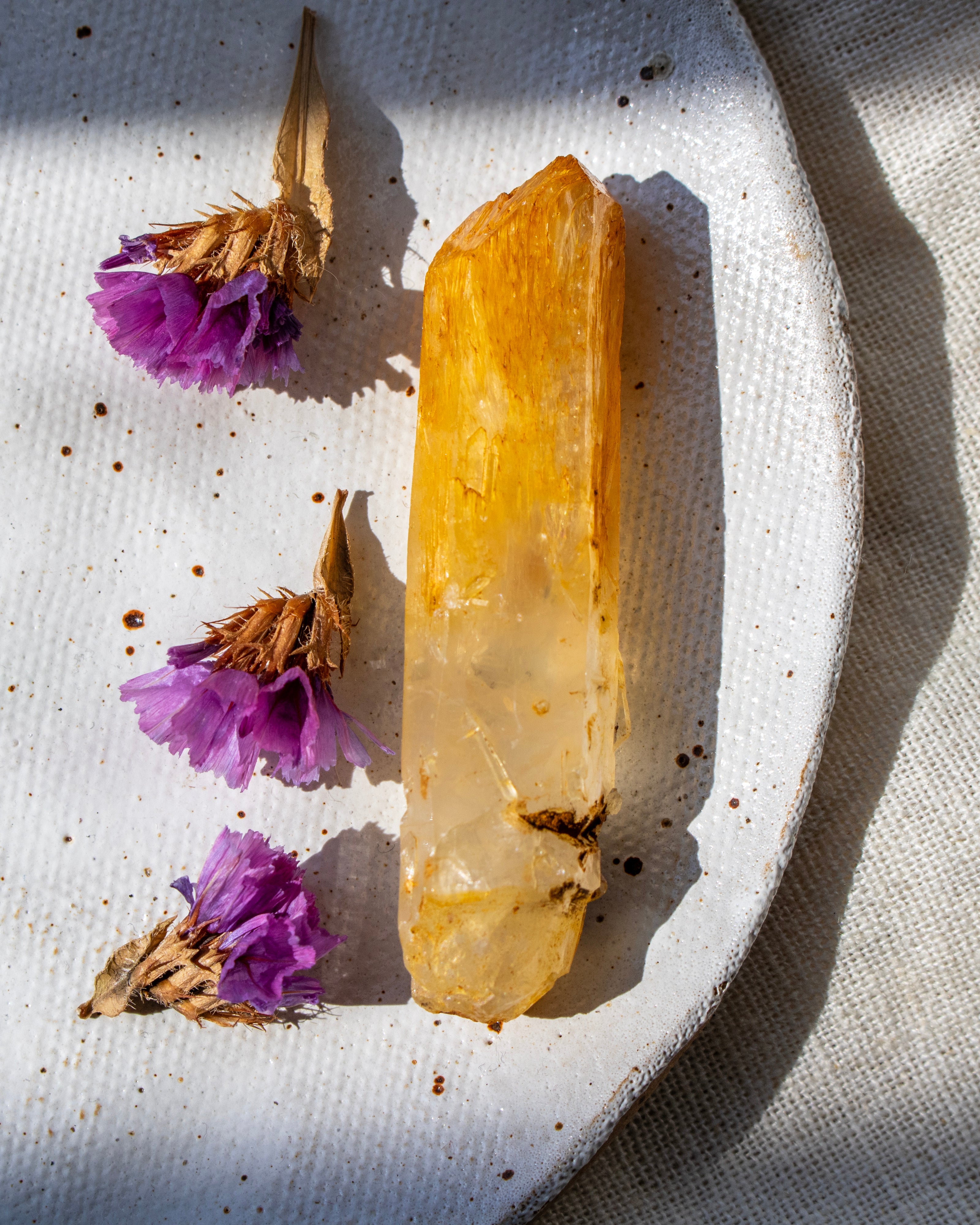 Clear crystal on a textured white surface with purple flowers