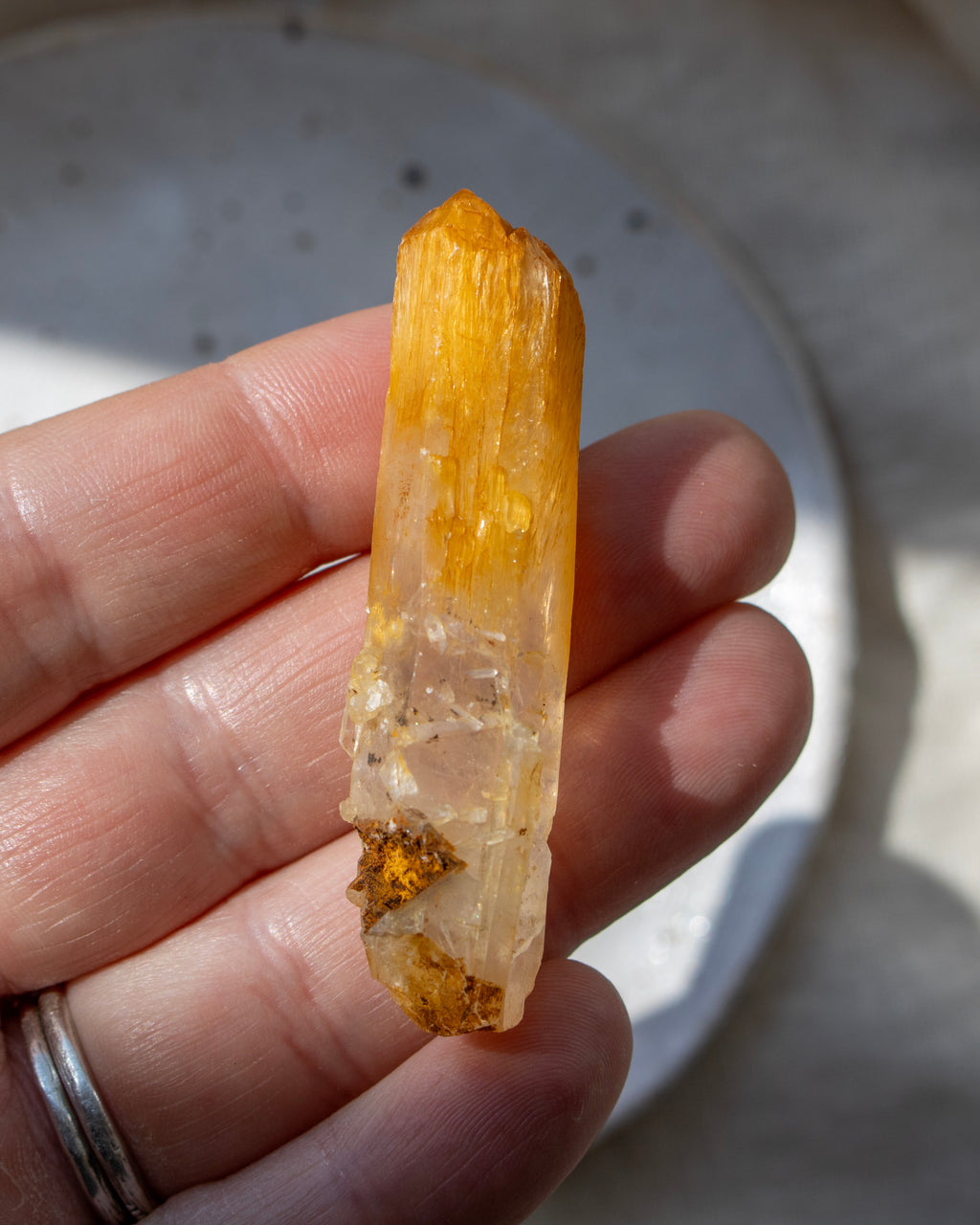 Hand holding a yellow crystal against a neutral background