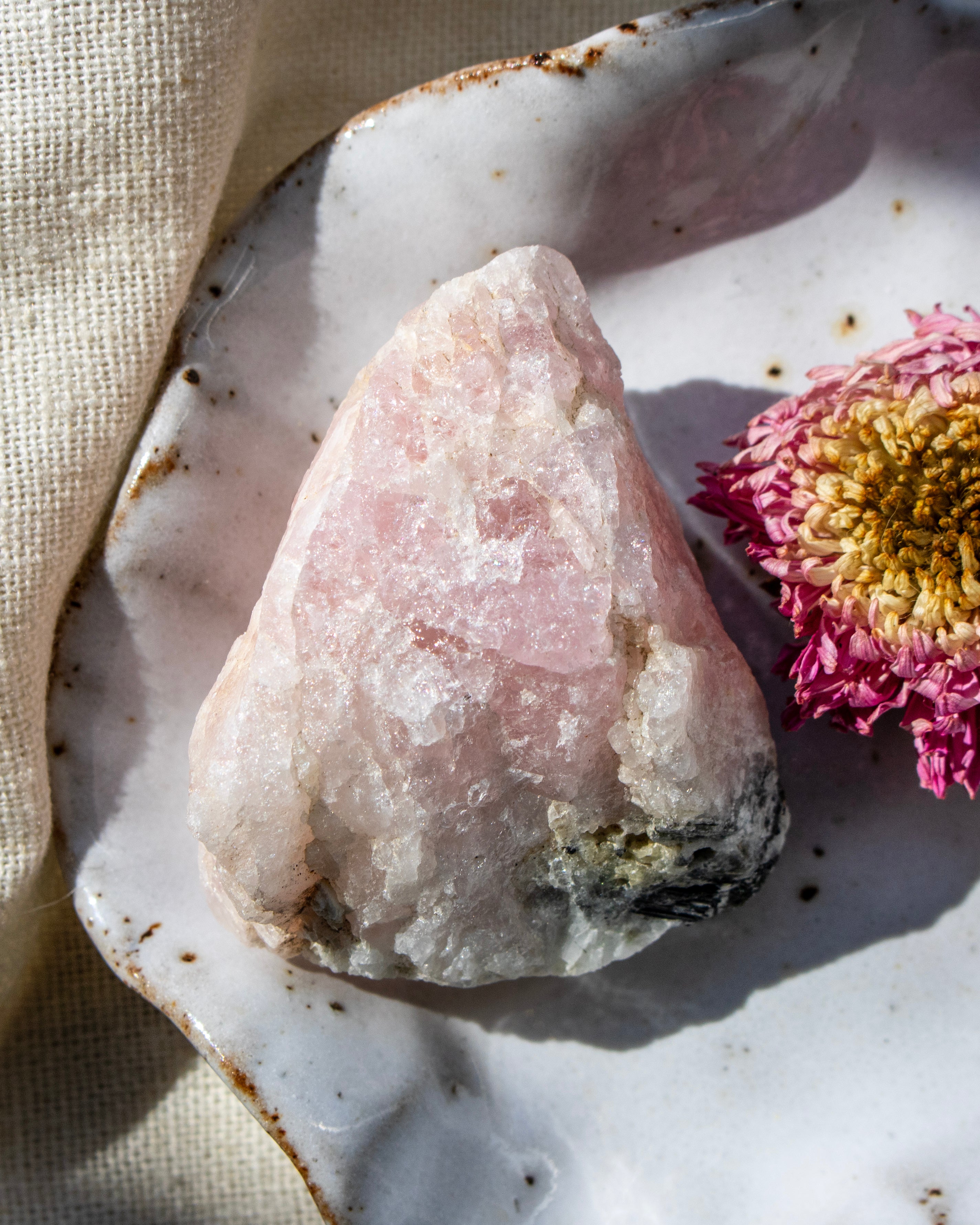 Pink crystal on a textured surface with a pink flower
