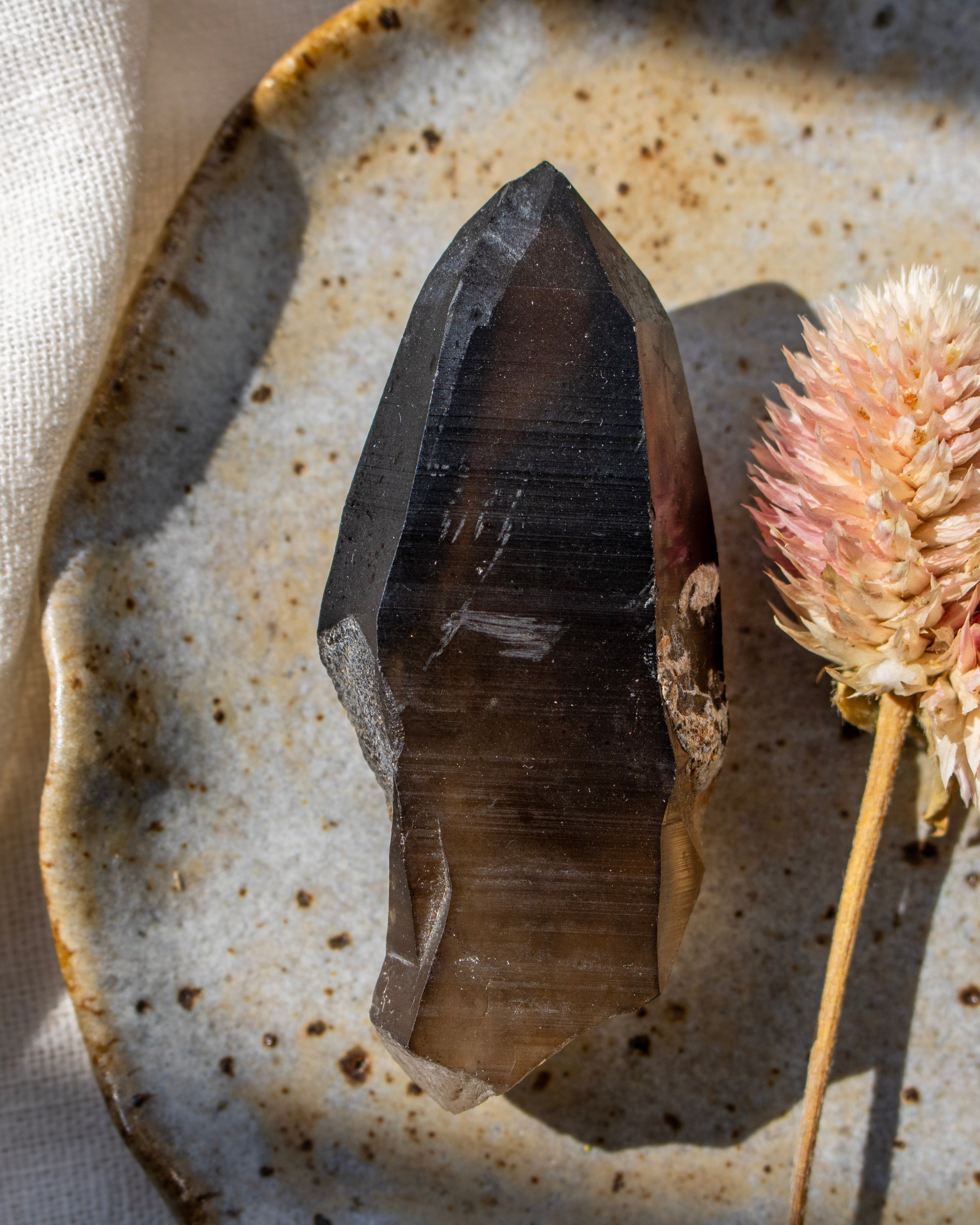 Crystal on a textured ceramic plate with a dried flower