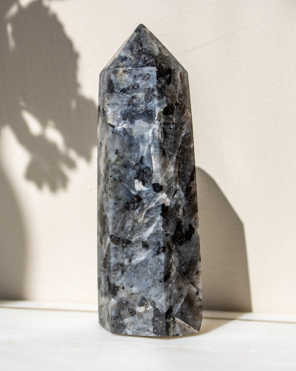 Decorative crystal tower with black speckles on a white surface