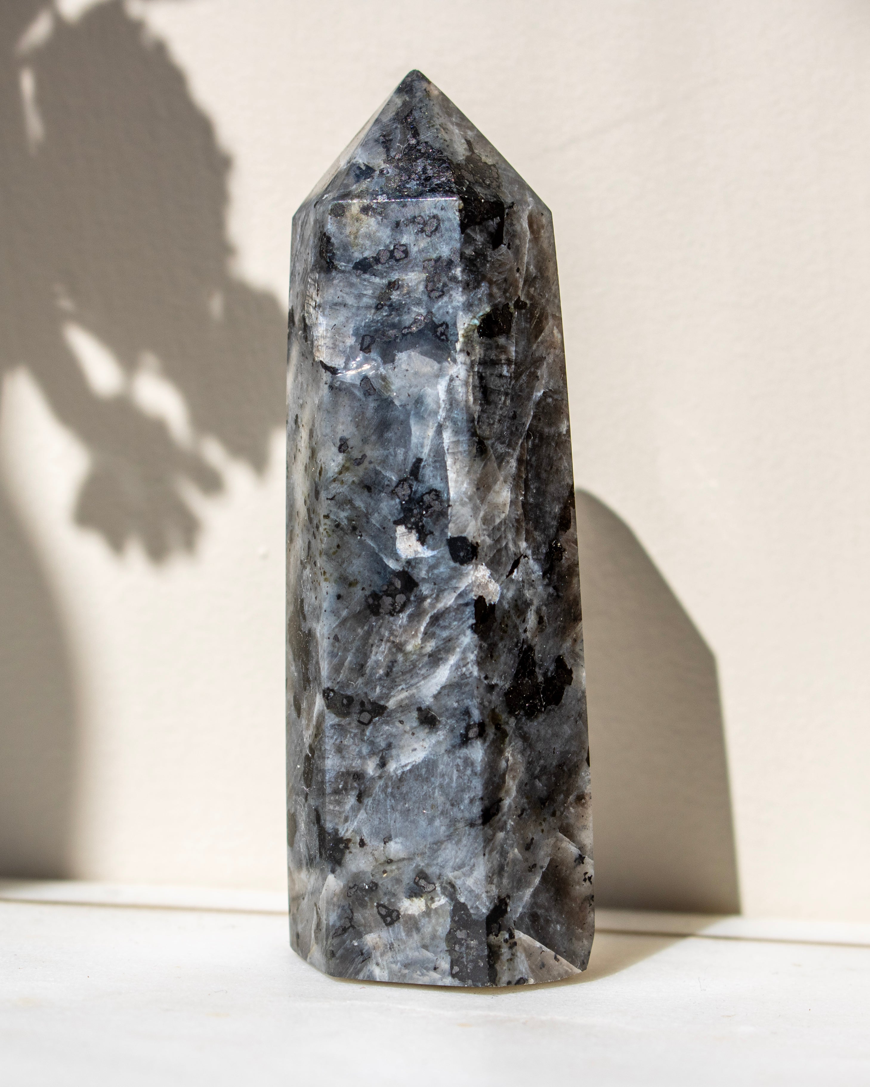 Decorative crystal tower with black speckles on a white surface