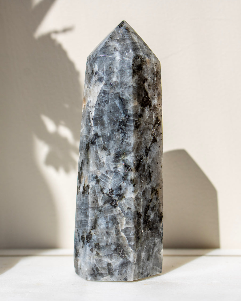 Tall, gray crystal tower on a white surface with a neutral background
