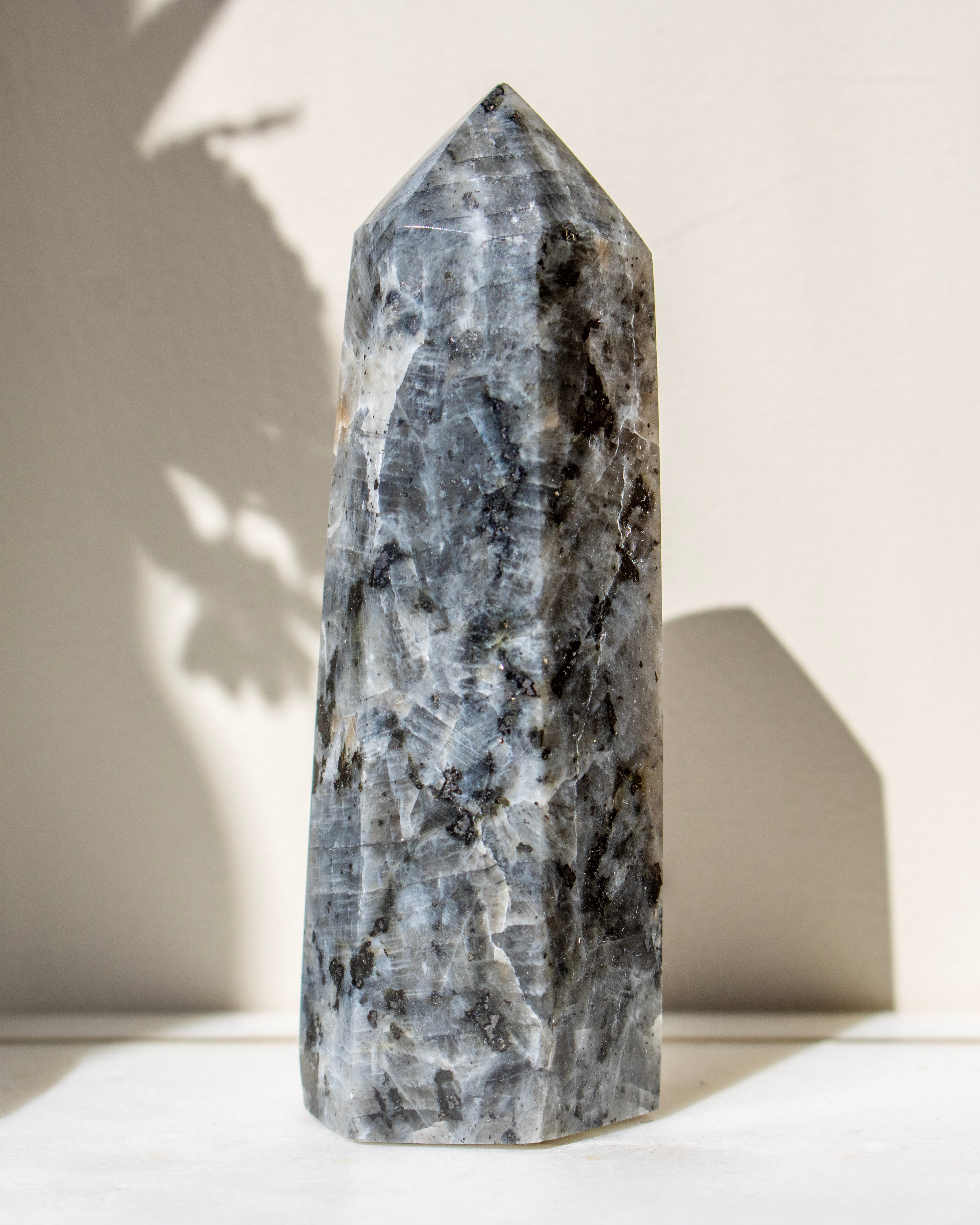 Tall, gray crystal tower on a white surface with a neutral background
