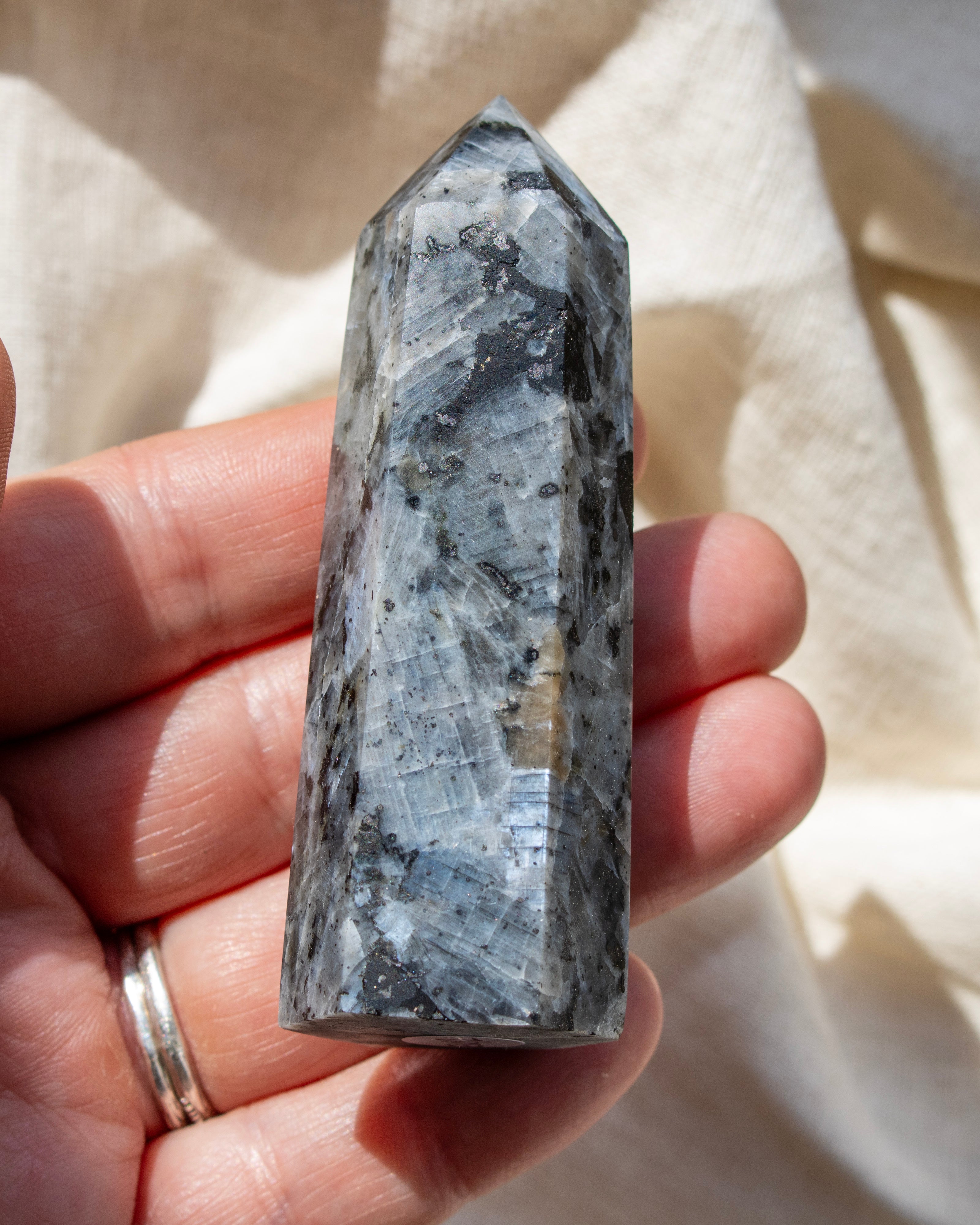 Hand holding a crystal with a neutral background
