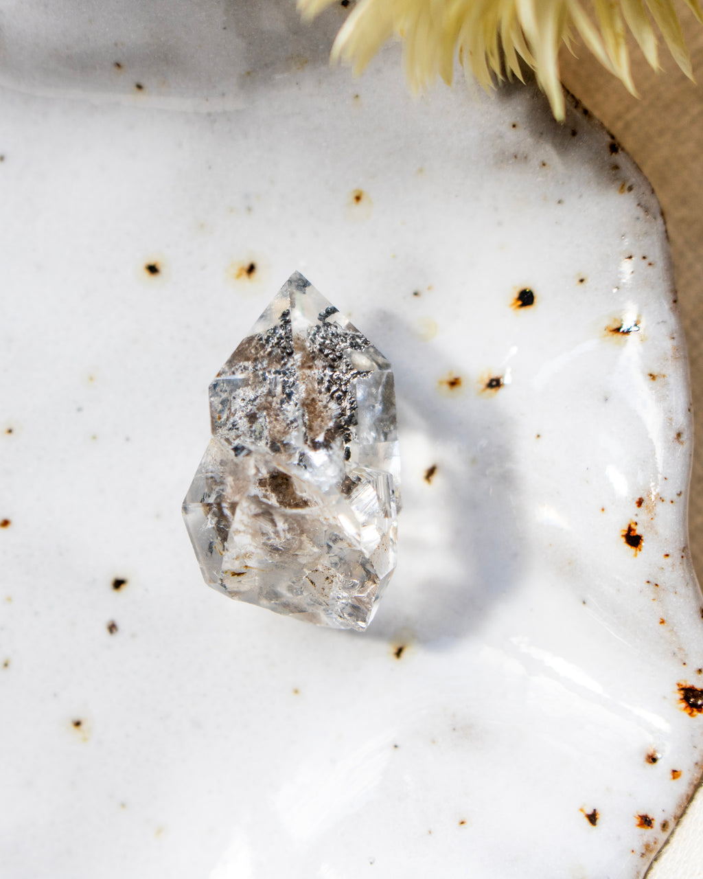 Clear crystal on a textured white surface with specks of brown