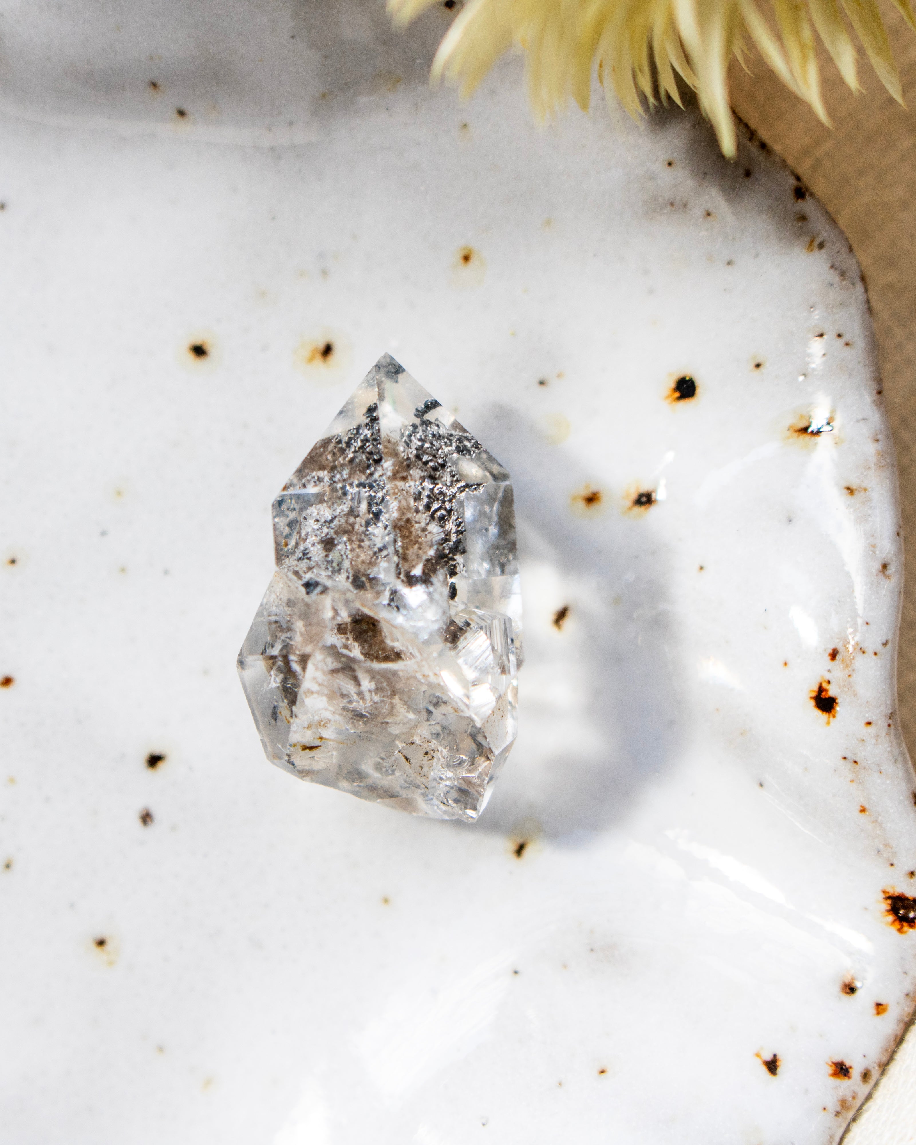 Clear crystal on a textured white surface with specks of brown