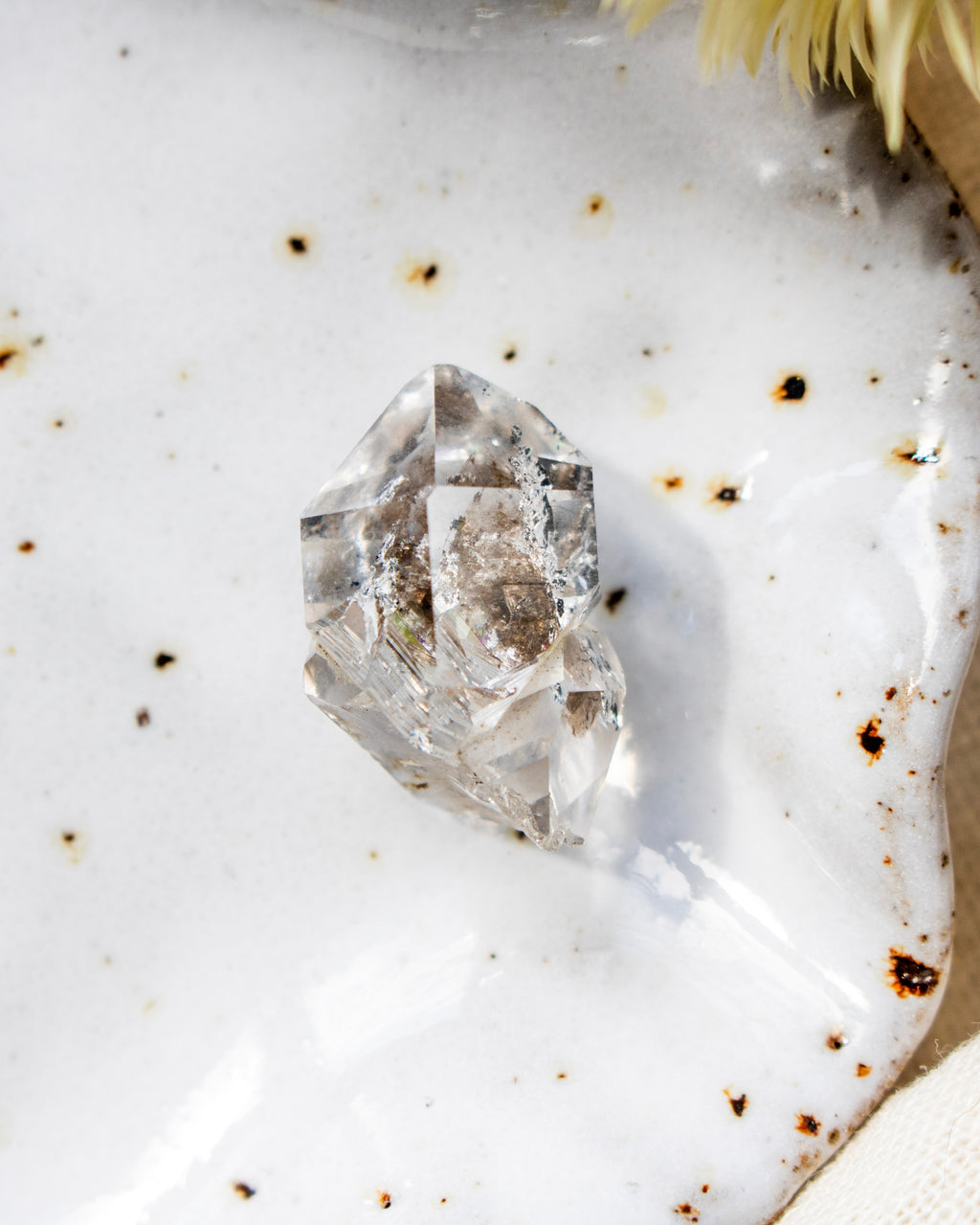 Clear crystal on a white surface with brown specks