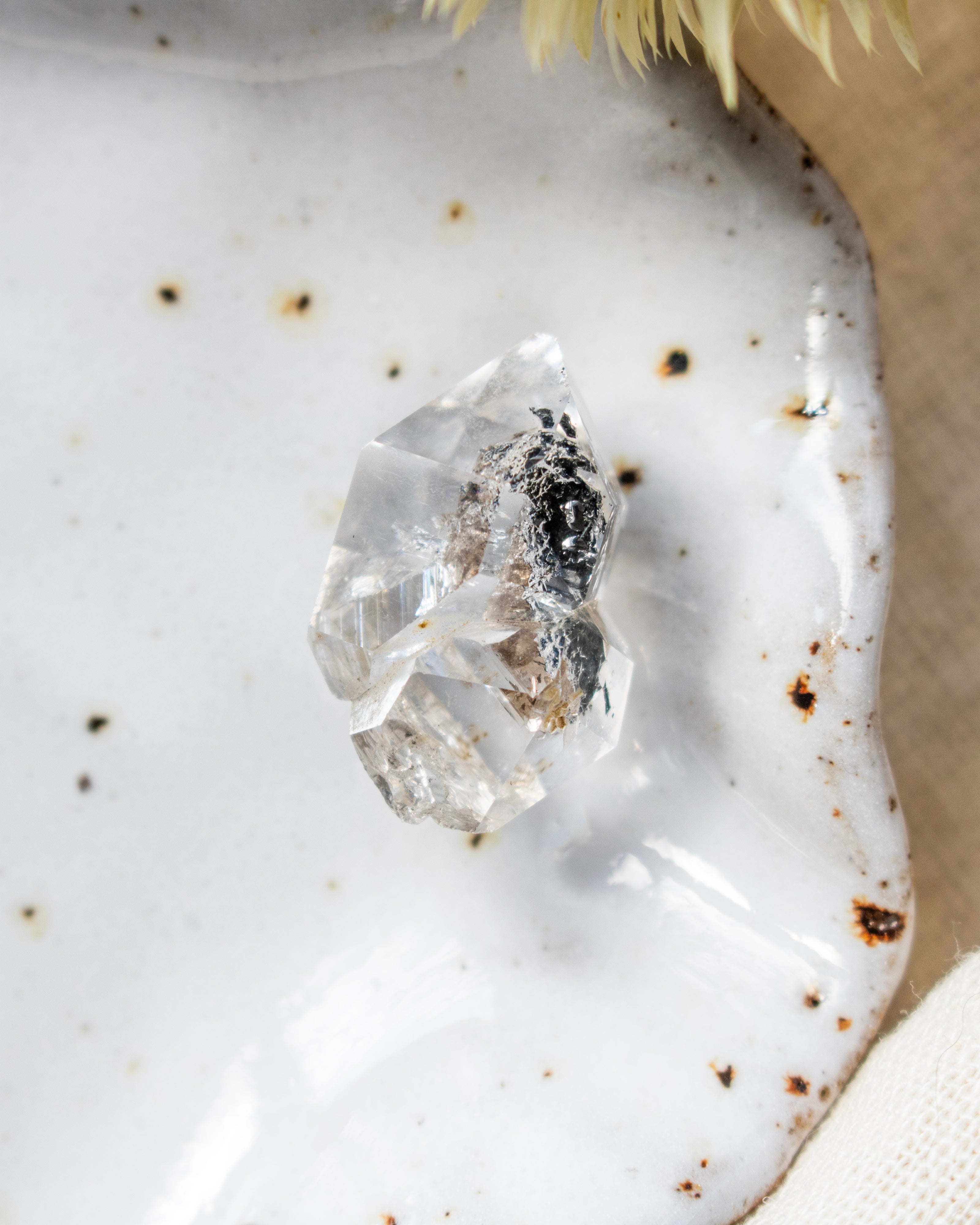 Clear crystal on a textured white surface with specks of brown