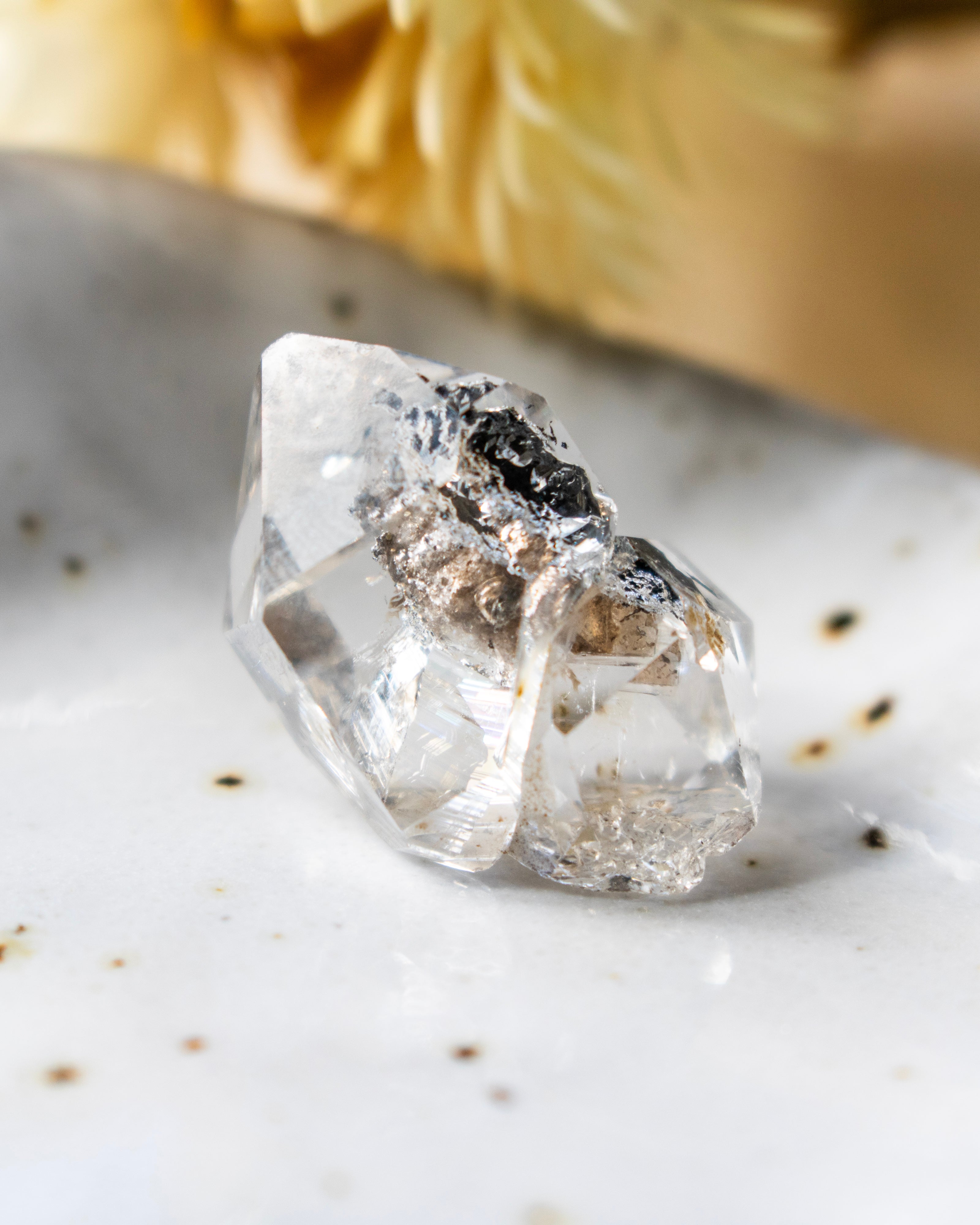 Clear crystal on a textured white surface with specks of brown