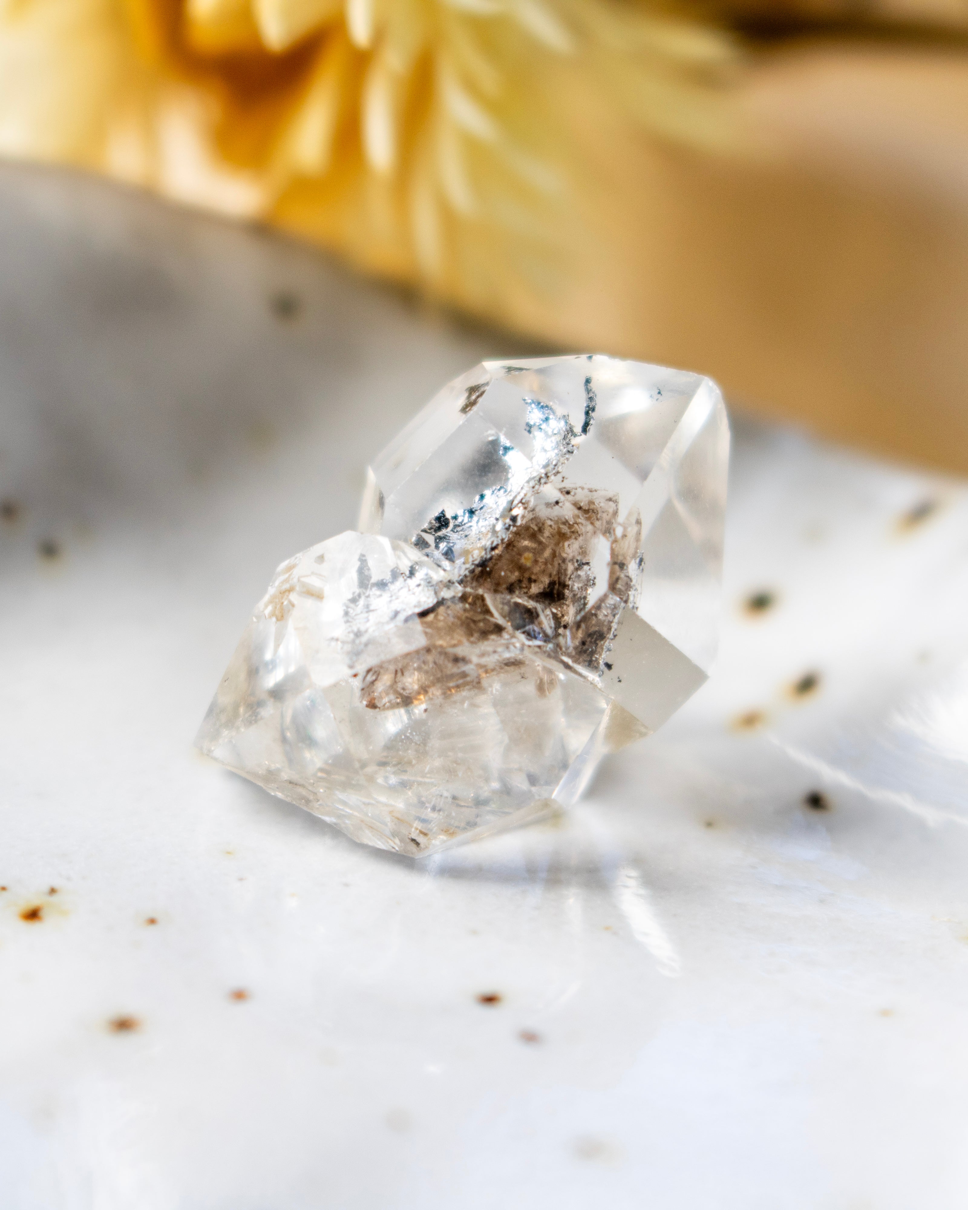Clear crystal on a textured white surface with specks of brown