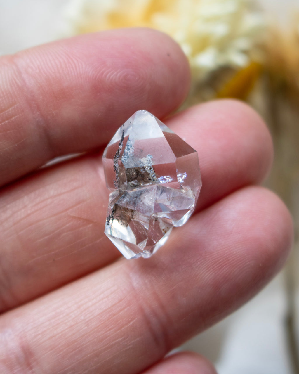 Clear crystal held between fingers with a blurred background