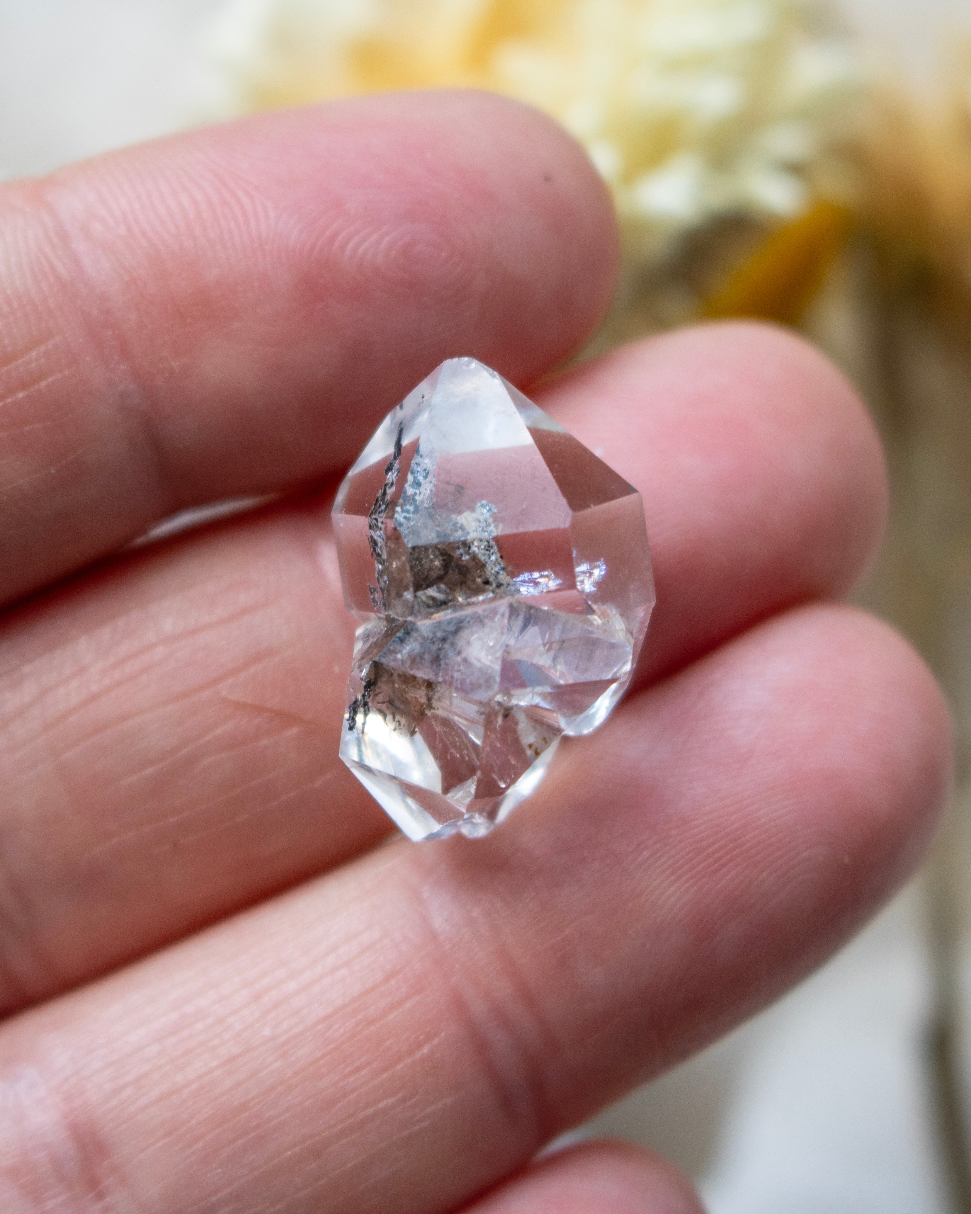 Clear crystal held between fingers with a blurred background