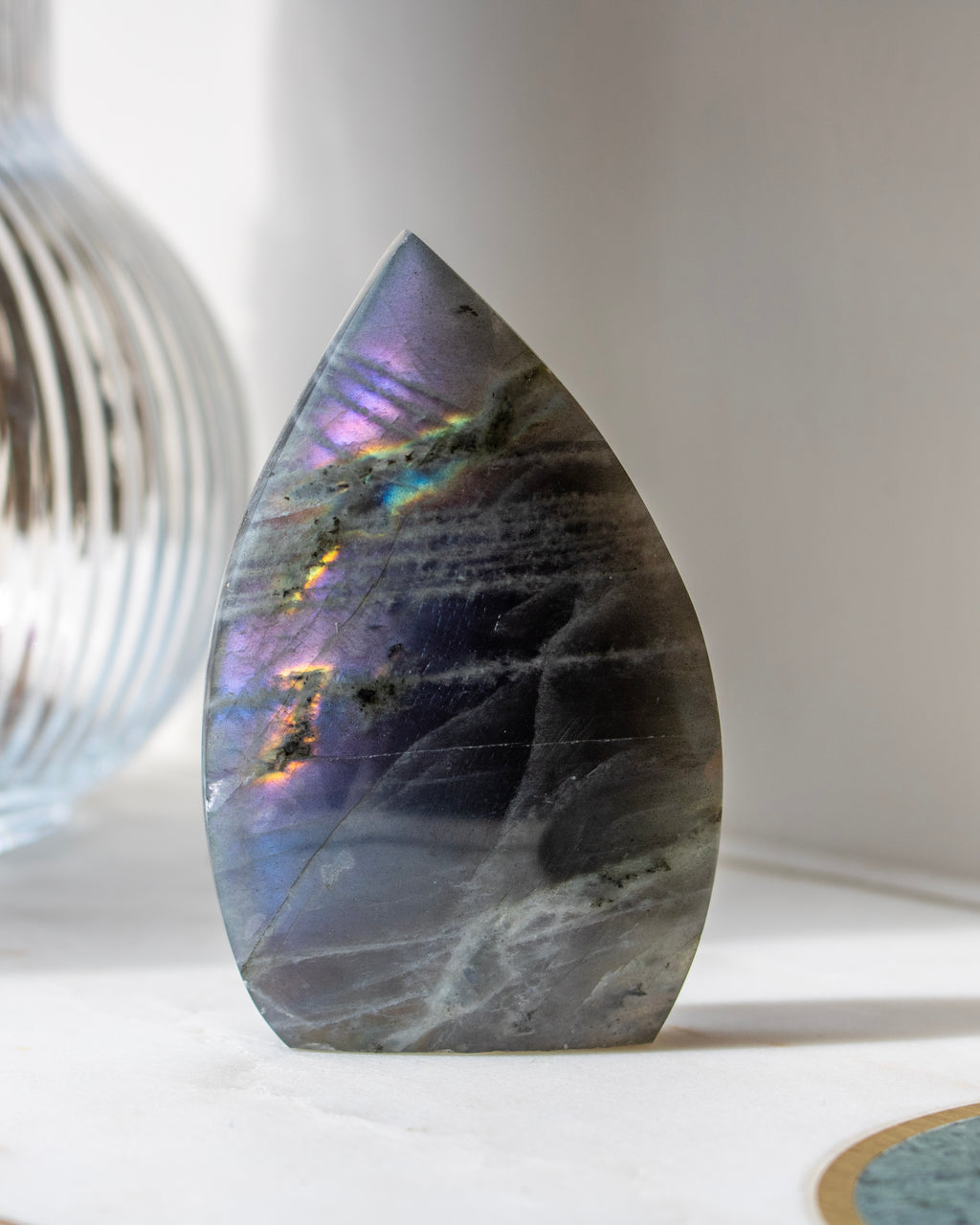 Teardrop-shaped stone with rainbow-like patterns on a white surface