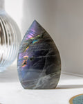Teardrop-shaped stone with rainbow-like patterns on a white surface