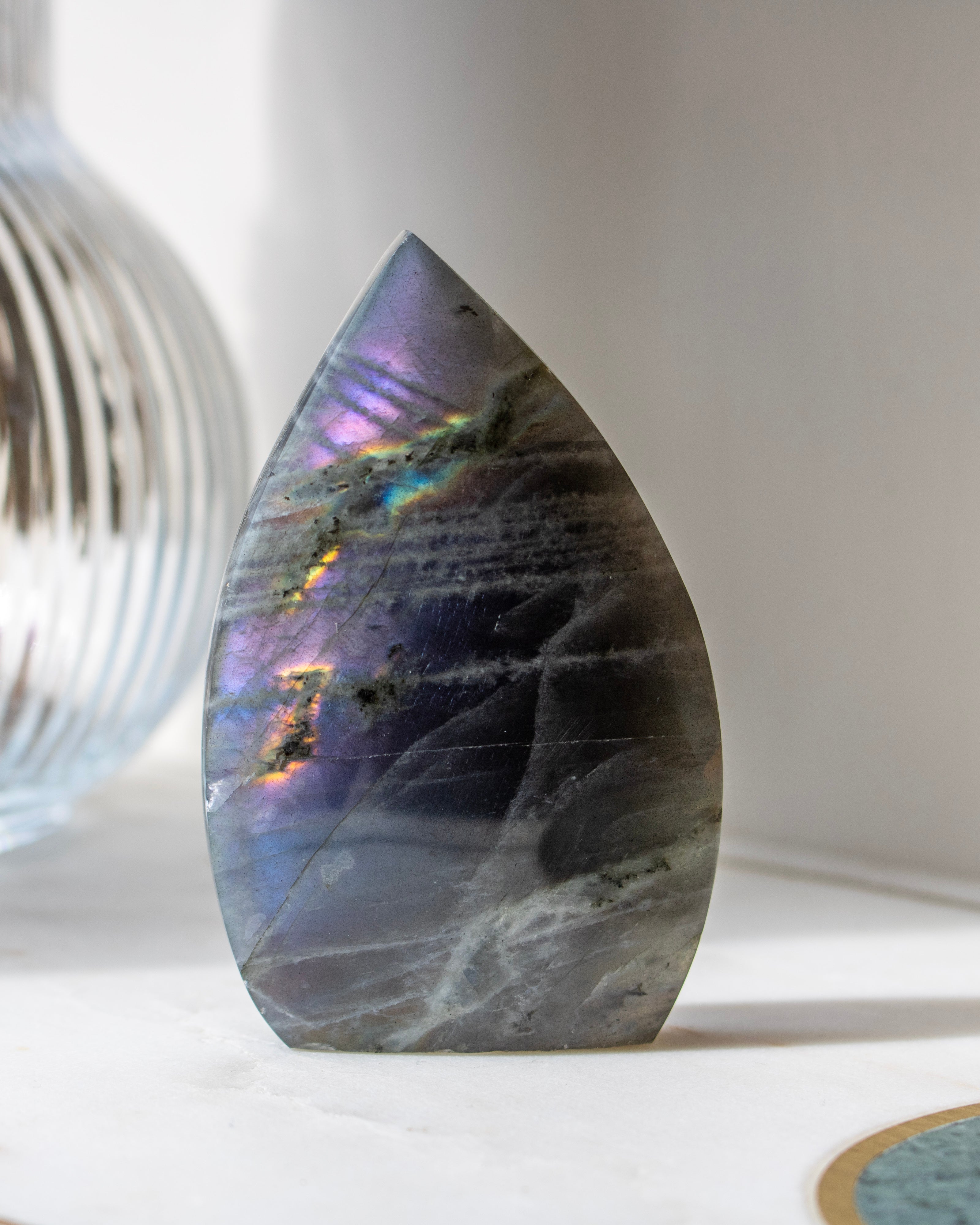 Teardrop-shaped stone with rainbow-like patterns on a white surface