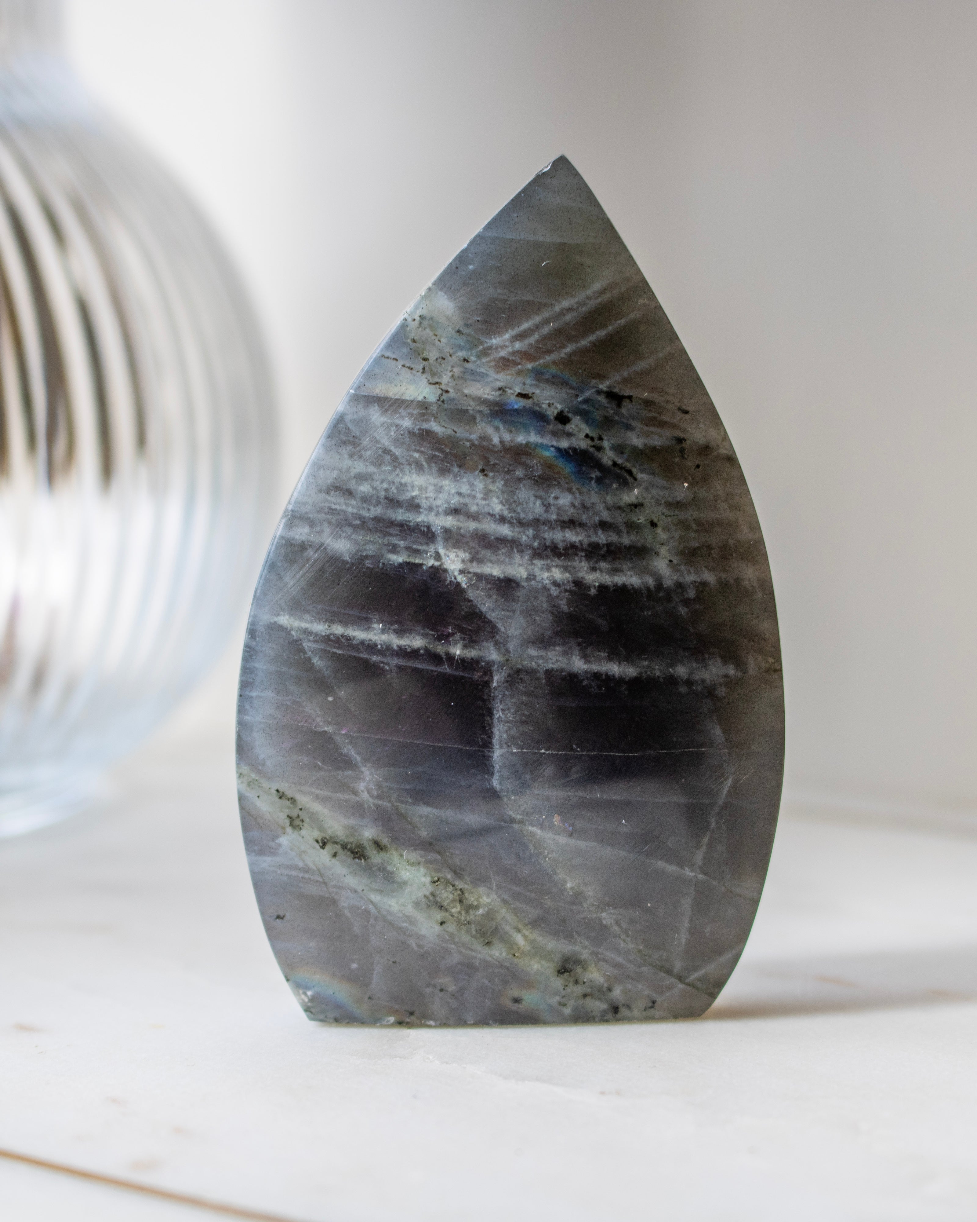 Teardrop-shaped stone with rainbow-like patterns on a white surface