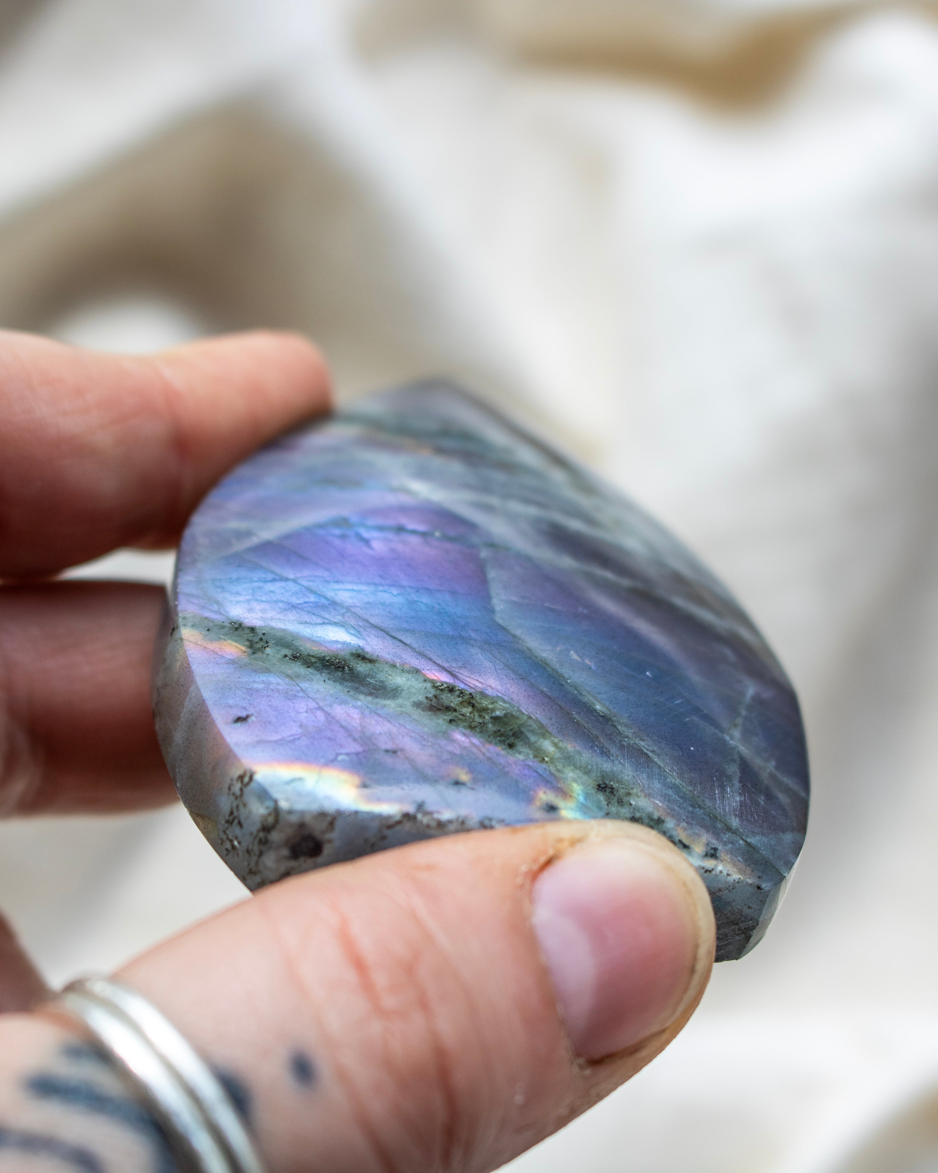 Teardrop-shaped stone with rainbow-like patterns on a white surface