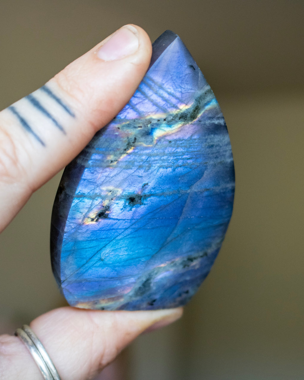 Teardrop-shaped blue stone held by a hand against a neutral background