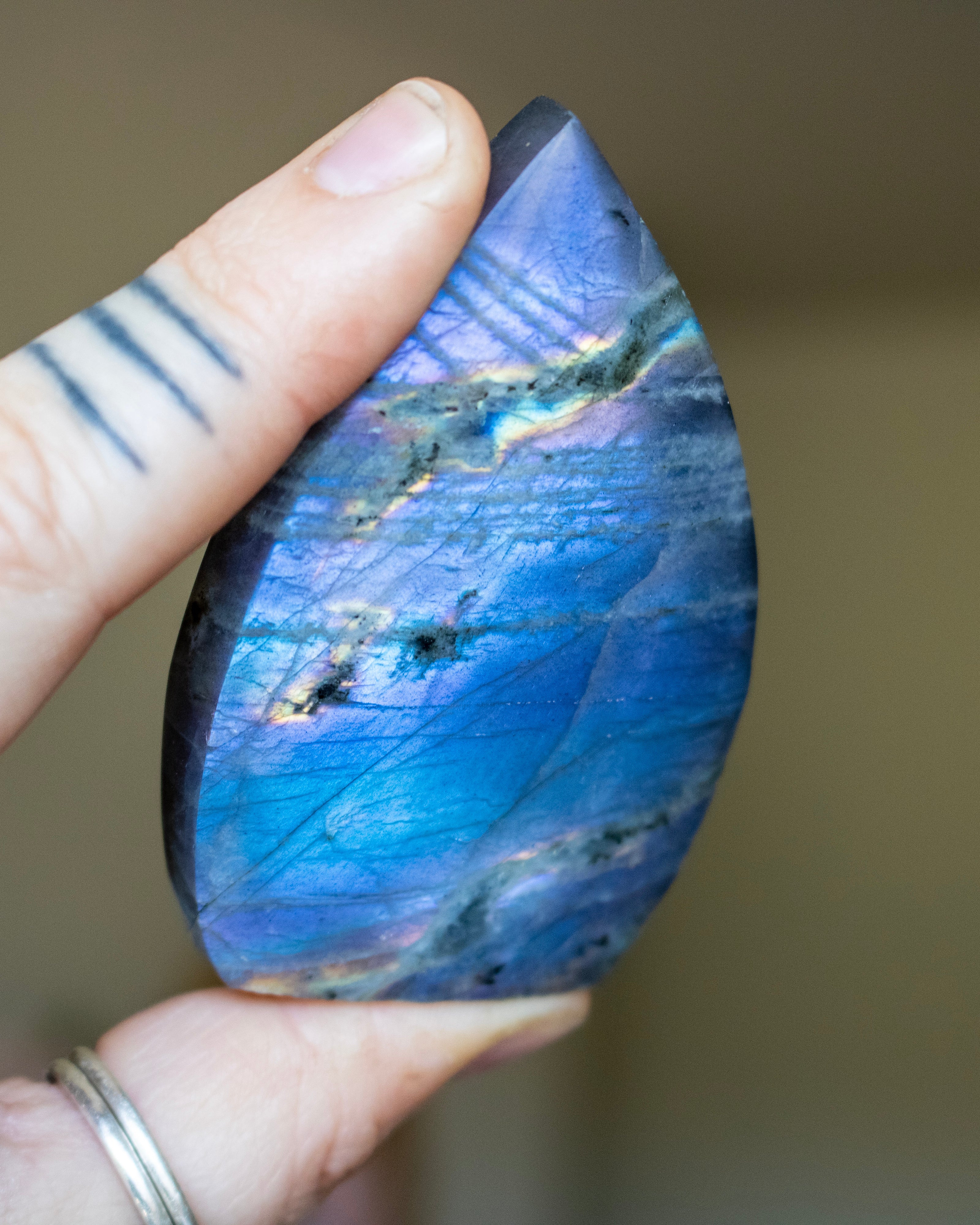 Teardrop-shaped blue stone held by a hand against a neutral background