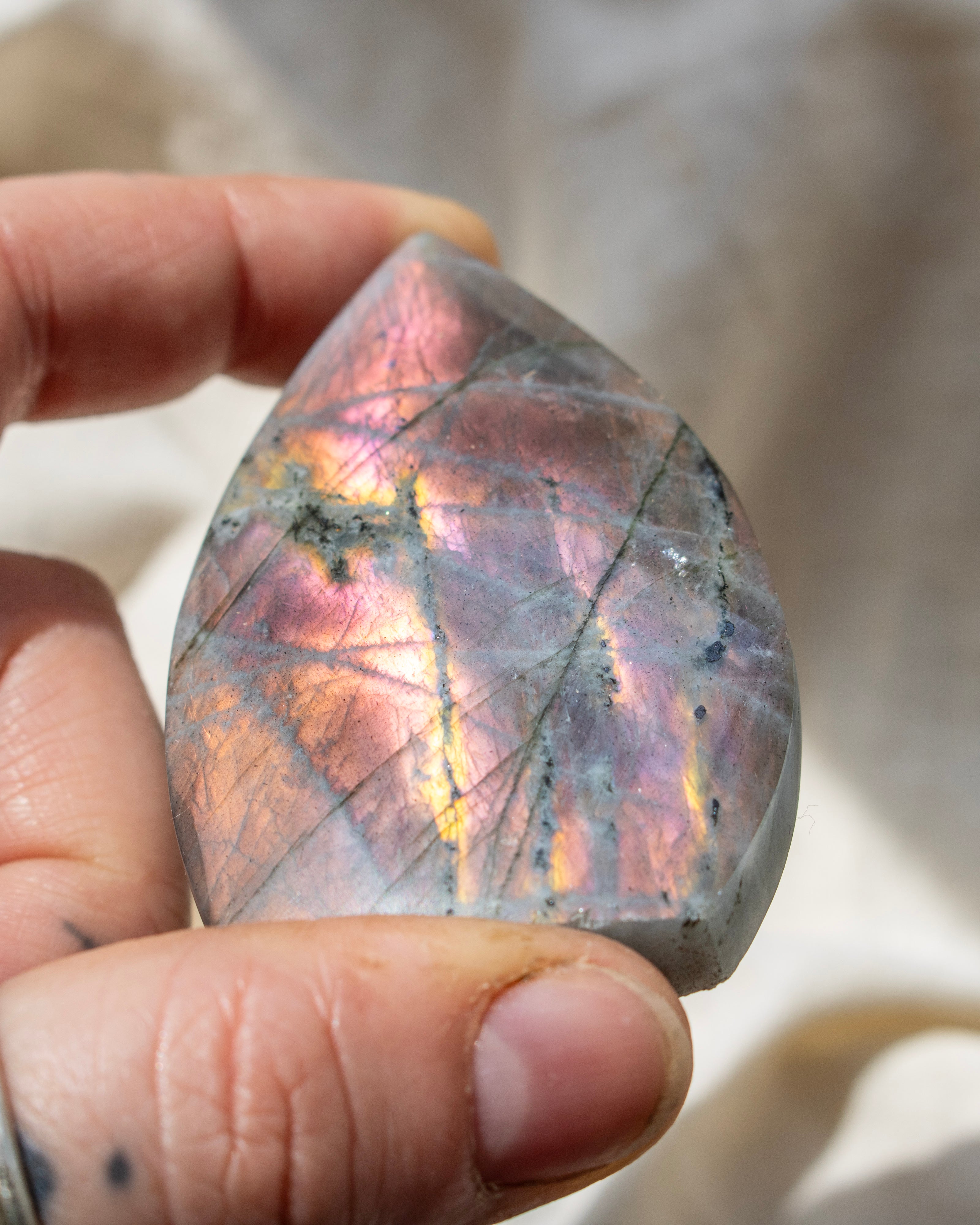 Person holding a colorful labradorite crystal