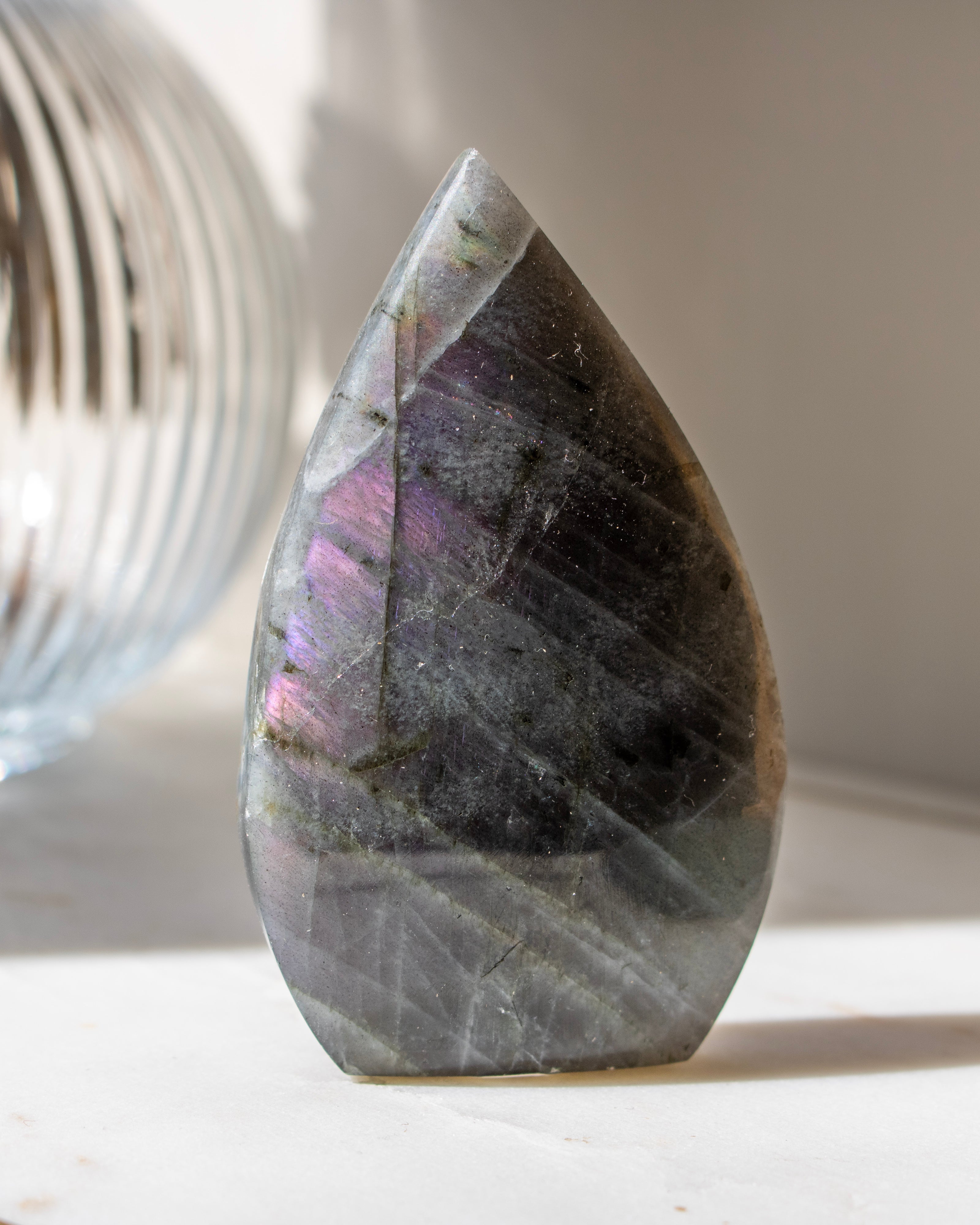 Teardrop-shaped crystal with multicolored patterns on a neutral background