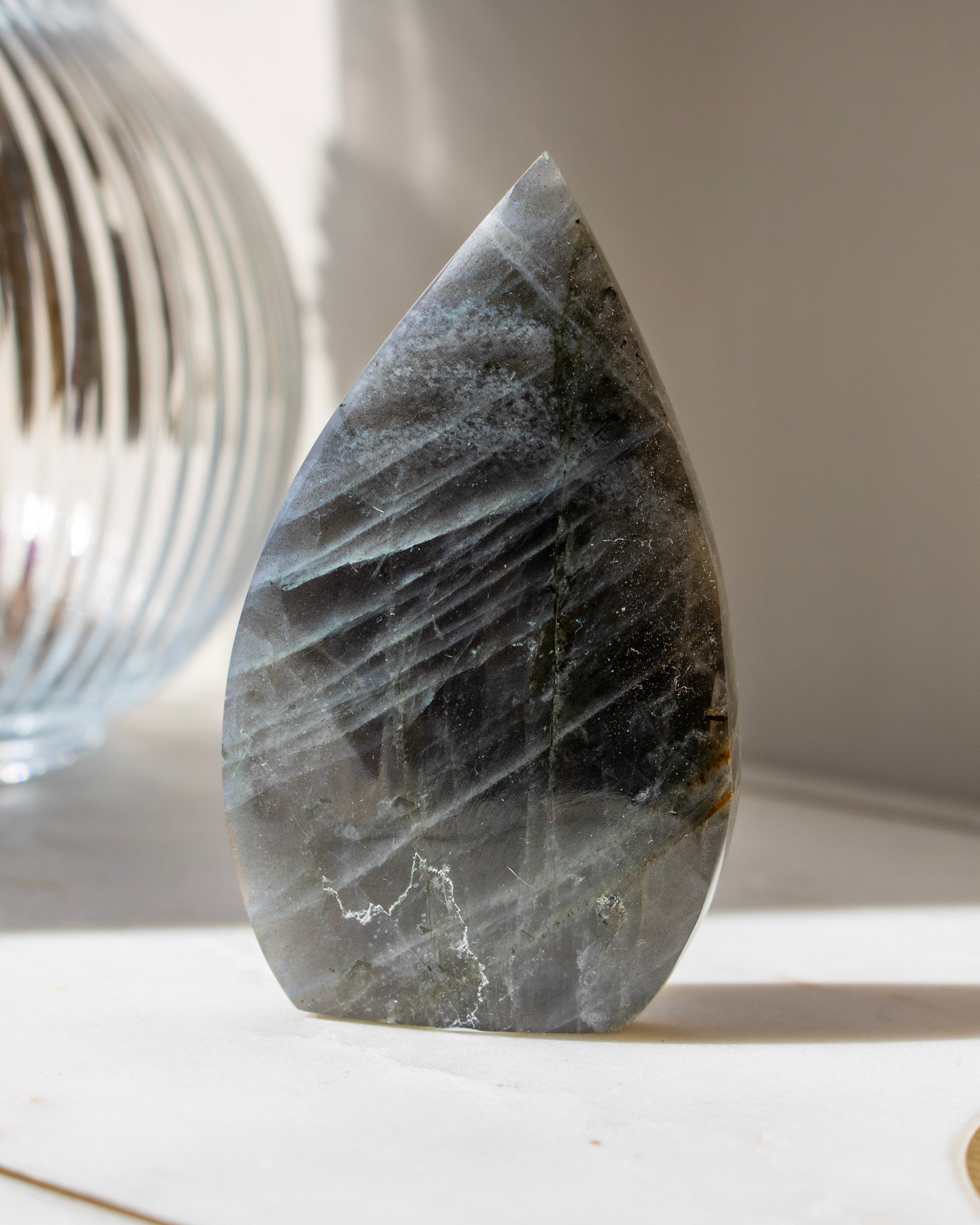 Teardrop-shaped crystal with multicolored patterns on a neutral background