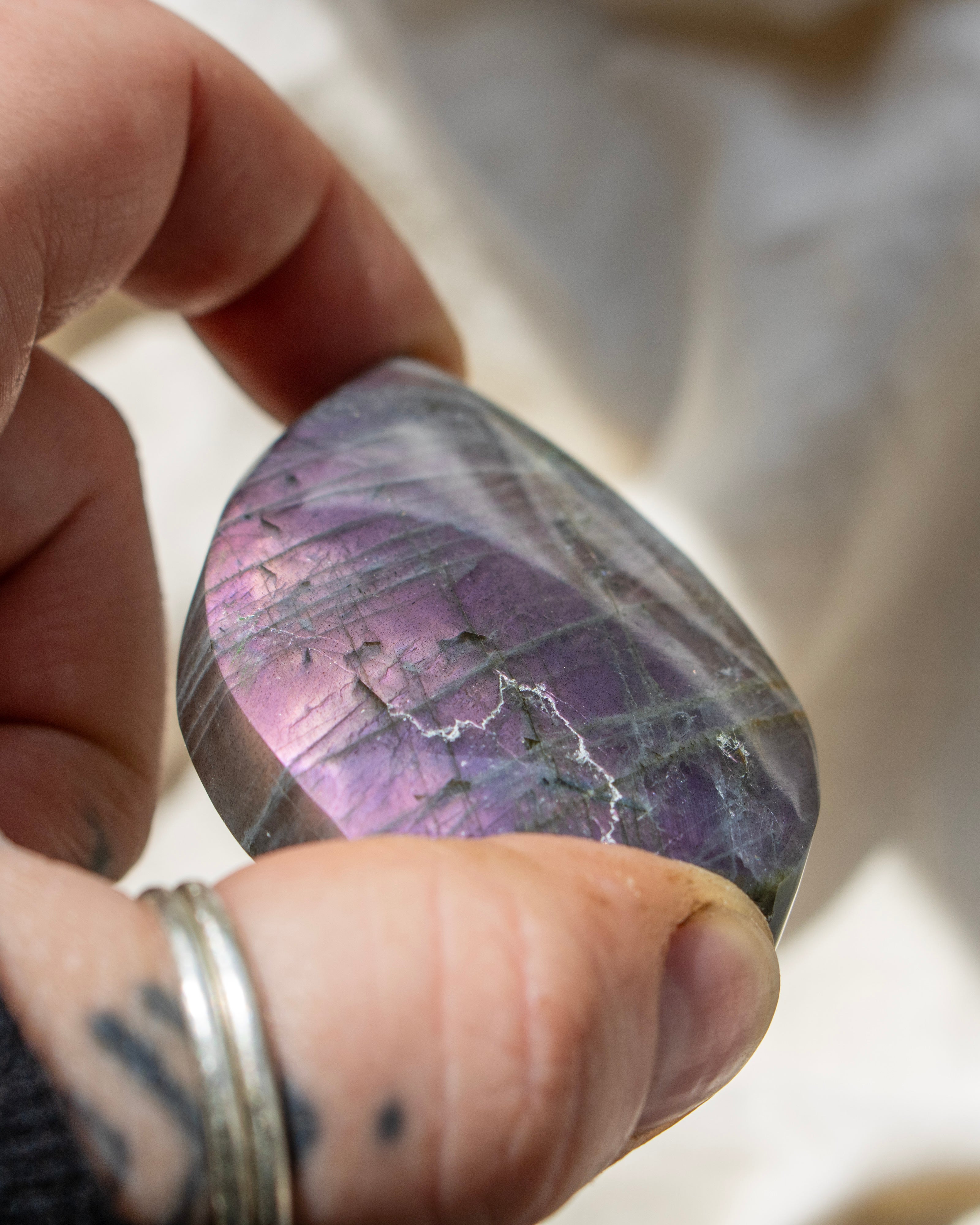 Hand holding a purple and green stone with a blurred background