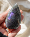 Teardrop-shaped crystal with multicolored patterns on a neutral background